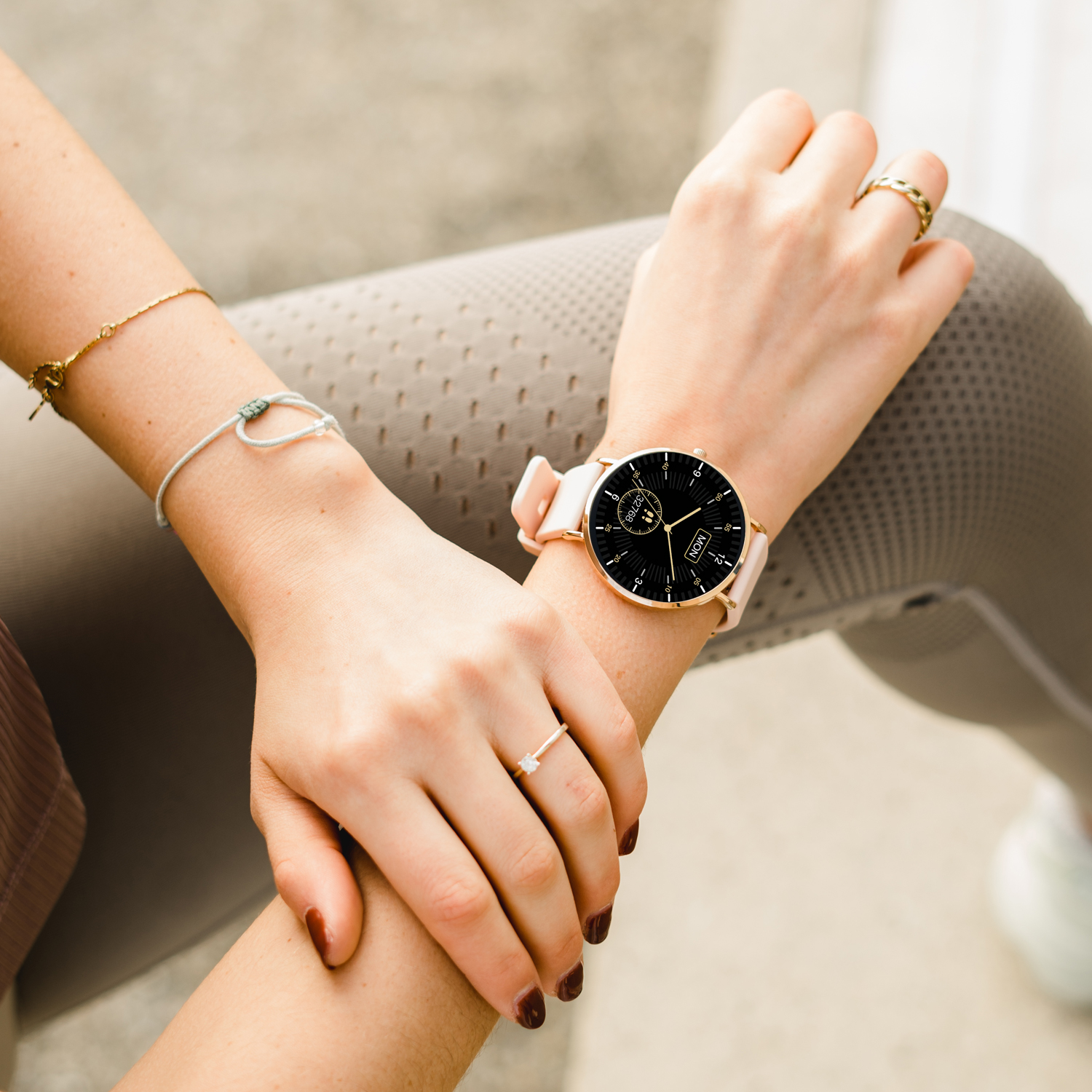 Das Handgelenk einer Frau mit goldener Uhr, Ringen und Armband.