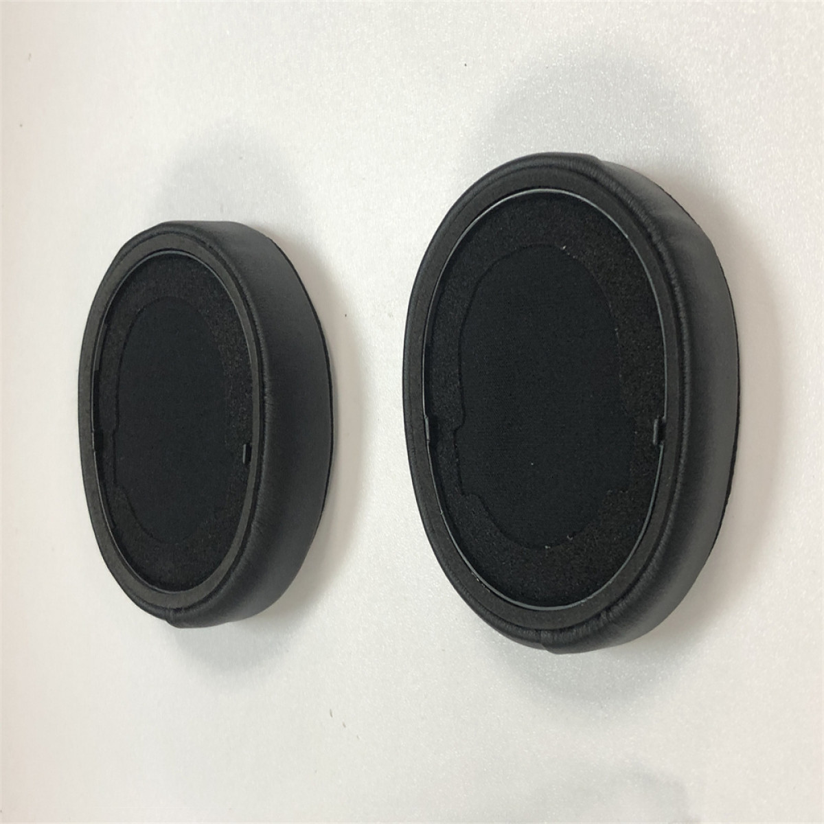 Due cuscinetti auricolari neri per cuffie. Sono rotondi e hanno un interno nero.