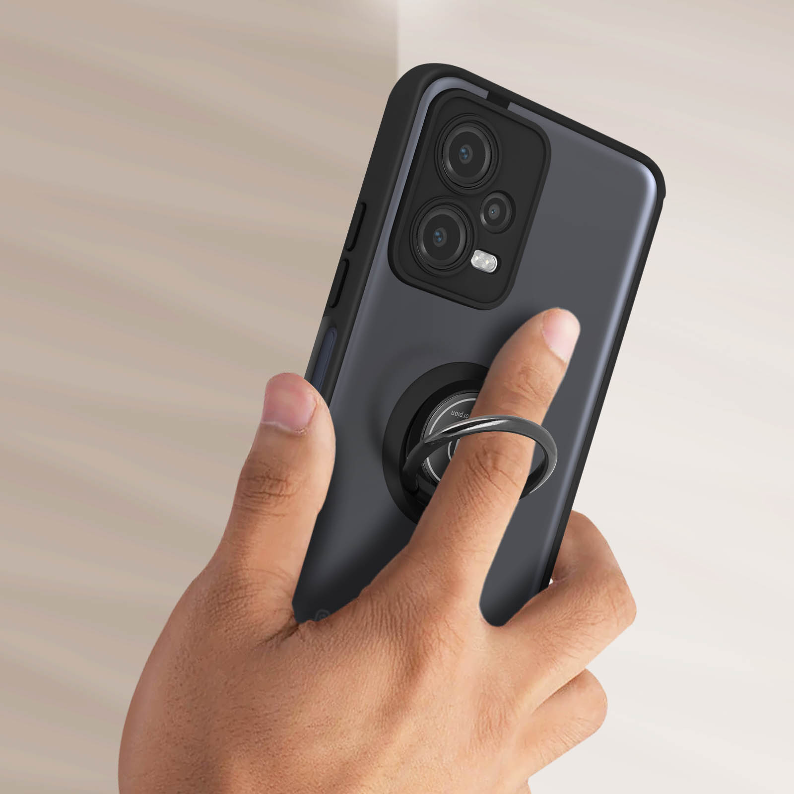 Mano che tiene un telefono con un anello di supporto, sfondo sfocato.