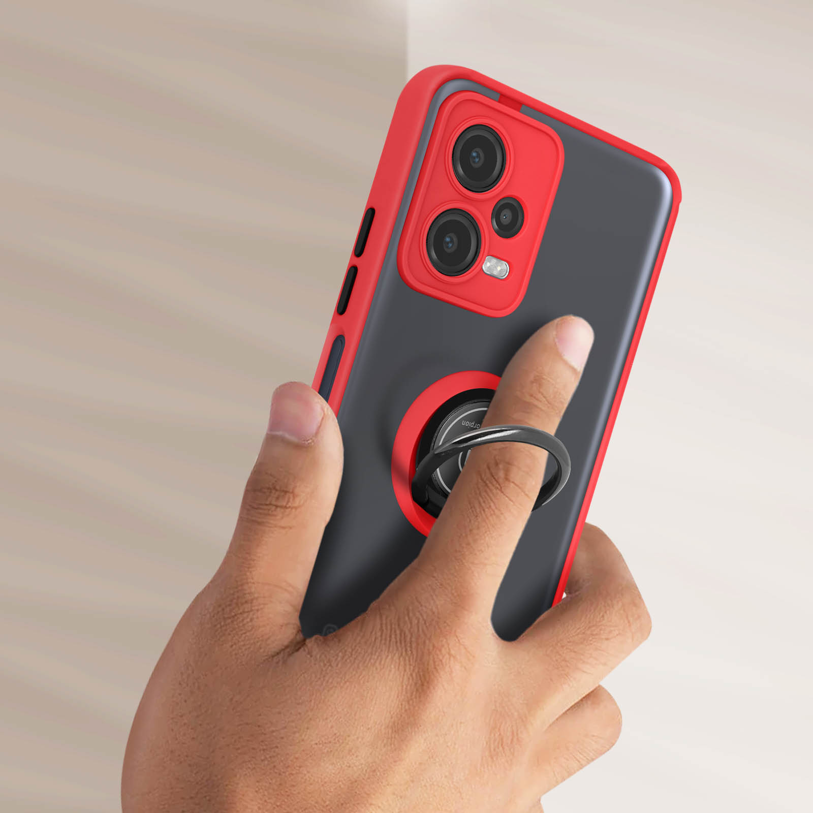 Hand, die eine rote Telefonhülle mit Ringhalter hält. Das Telefon hat einen dunklen Bildschirm. Der Hintergrund ist verschwommen.