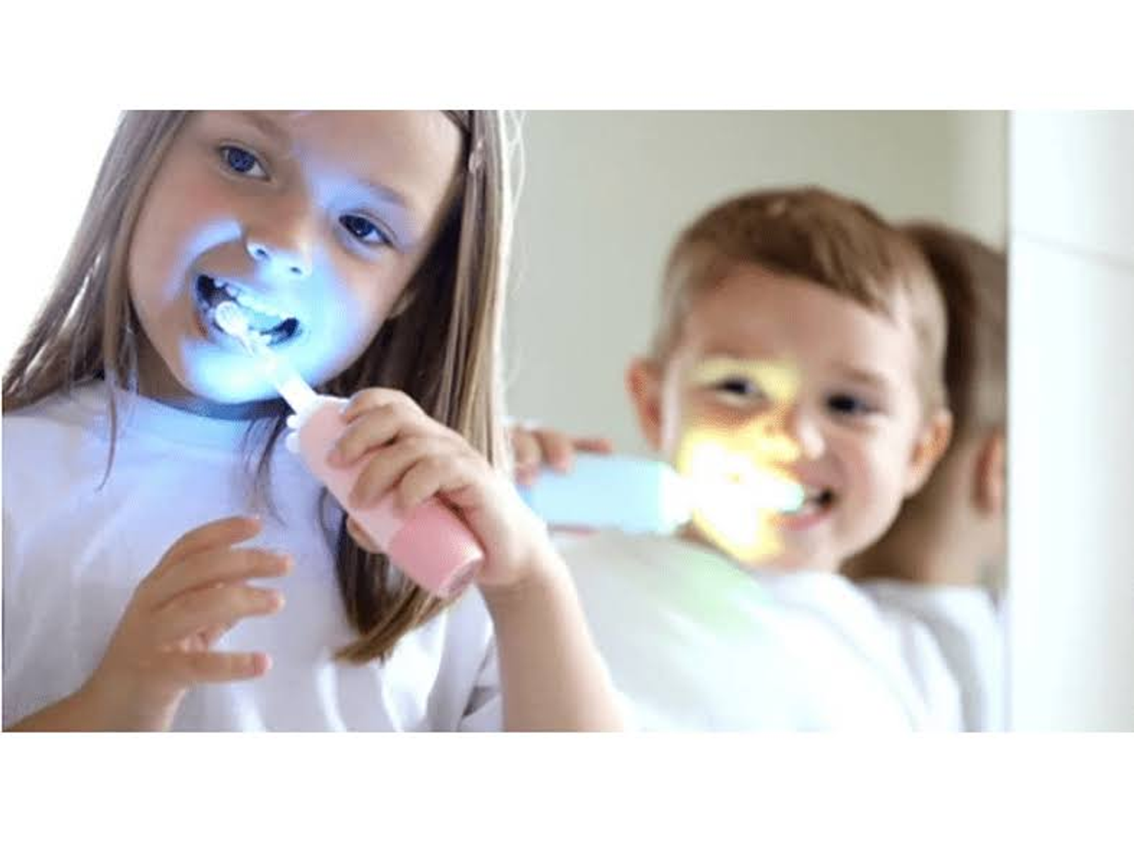 Due bambini che si lavano i denti con spazzolini che emettono luce blu e gialla.