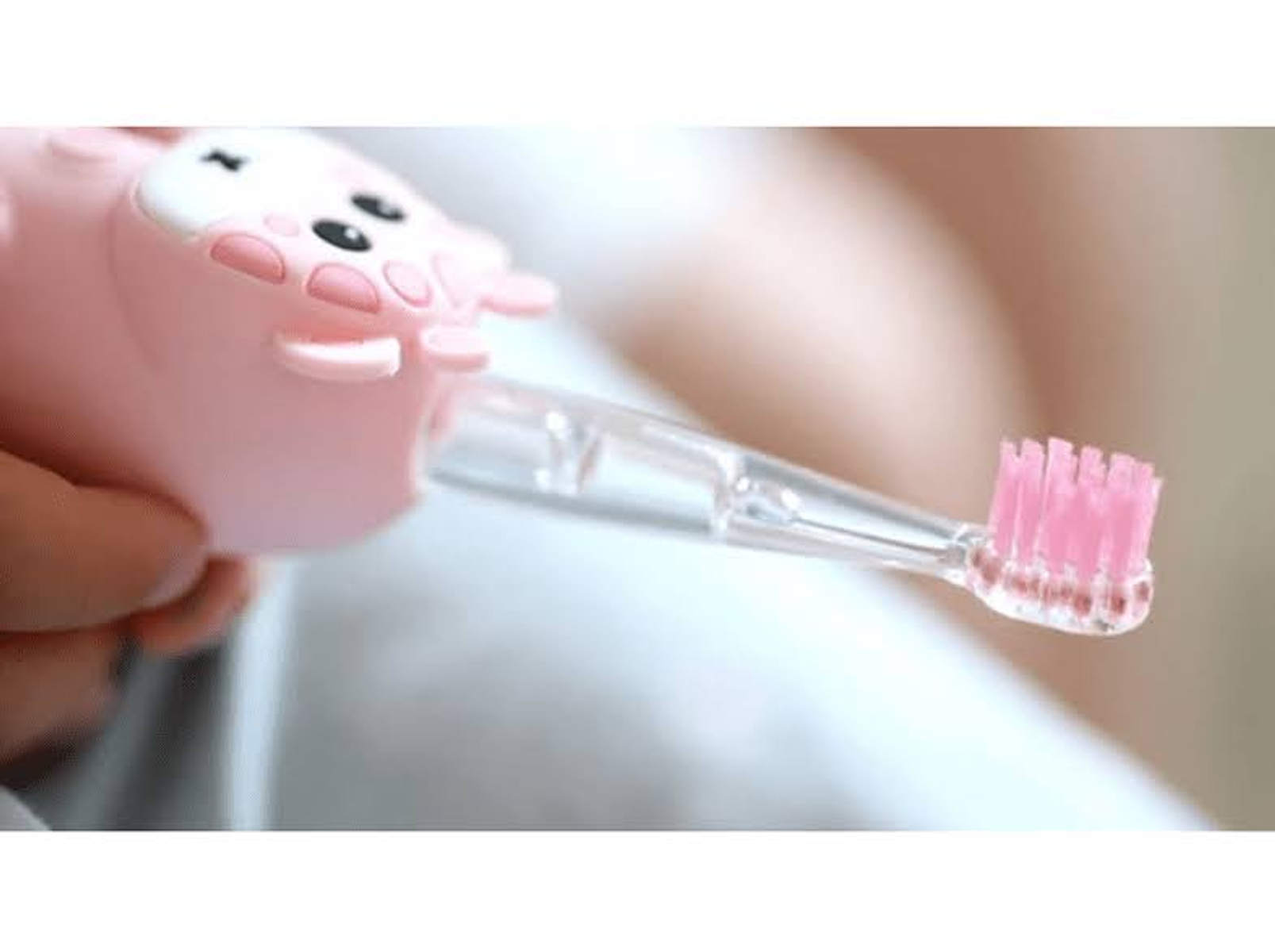 Spazzolino elettrico rosa. Testina rosa e piccolo animale dei cartoni animati sopra.