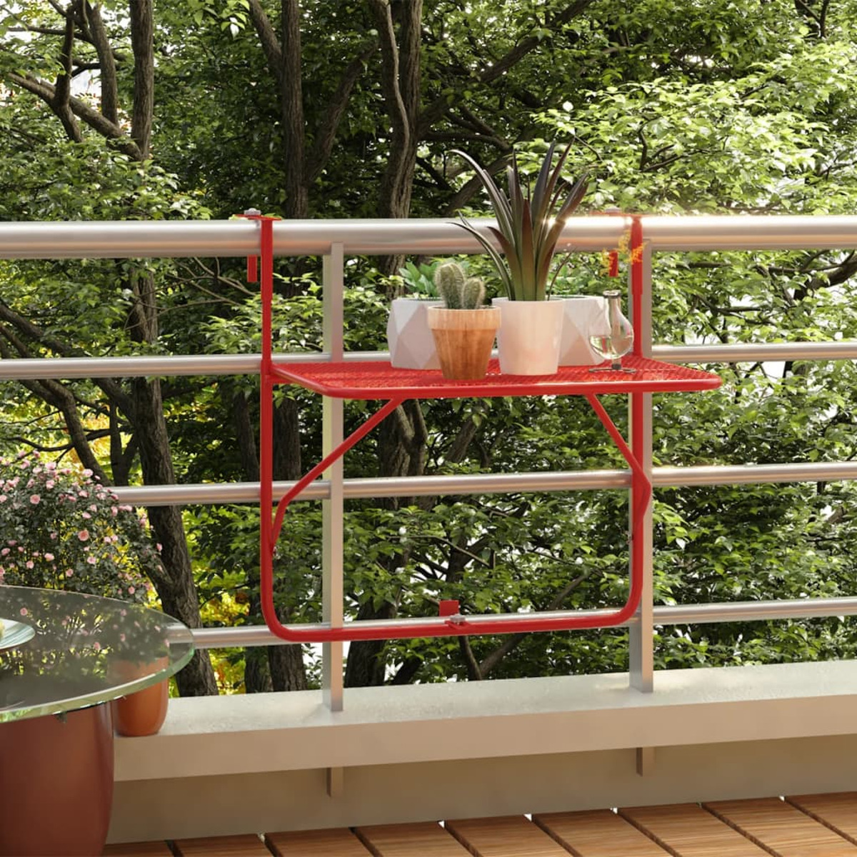 Roter Metall-Balkontisch mit Pflanzen, auf einem Balkon mit Laub im Hintergrund.