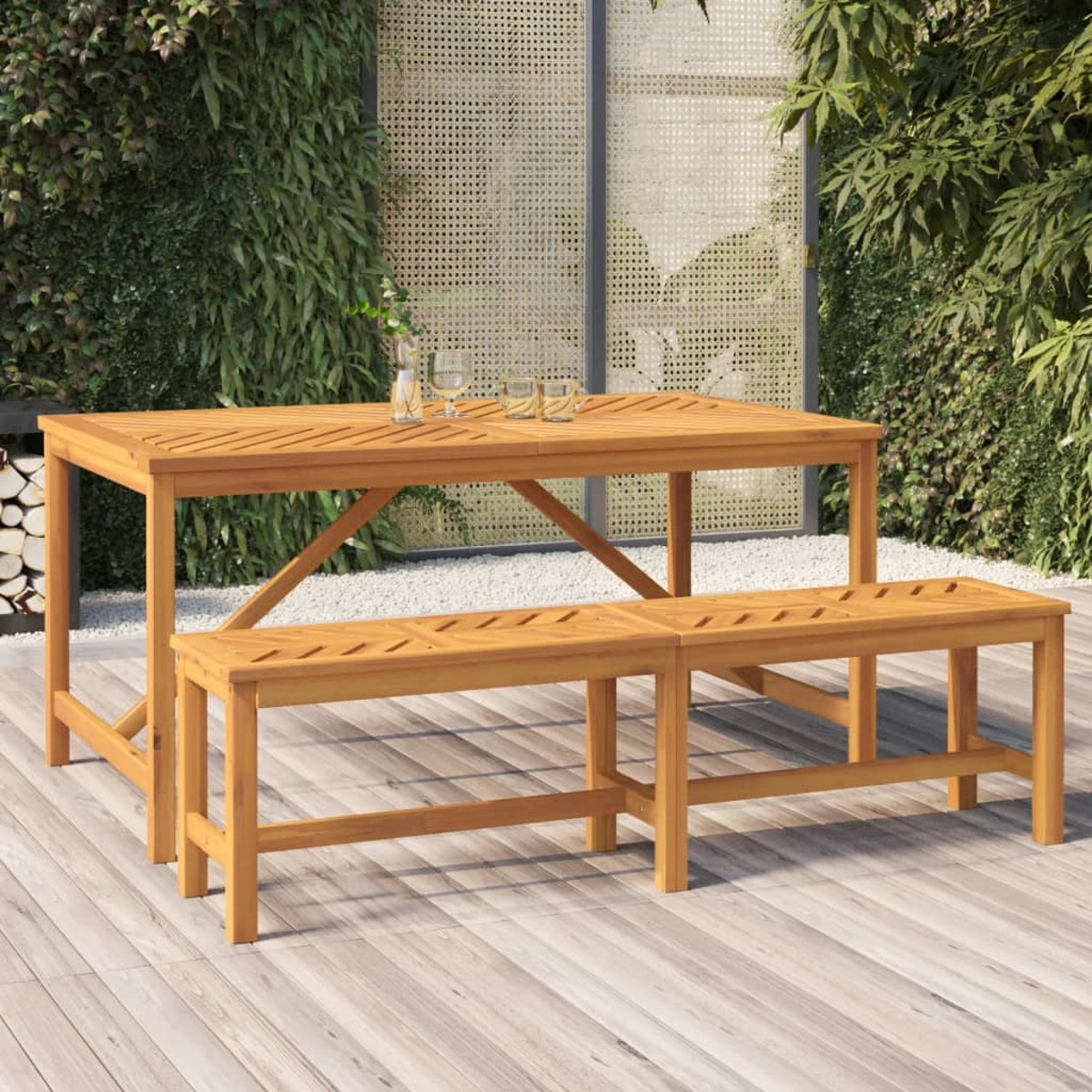 Holz-Gartentisch und -Bänke. Im Hintergrund eine grüne Wand und ein Holzzaun.