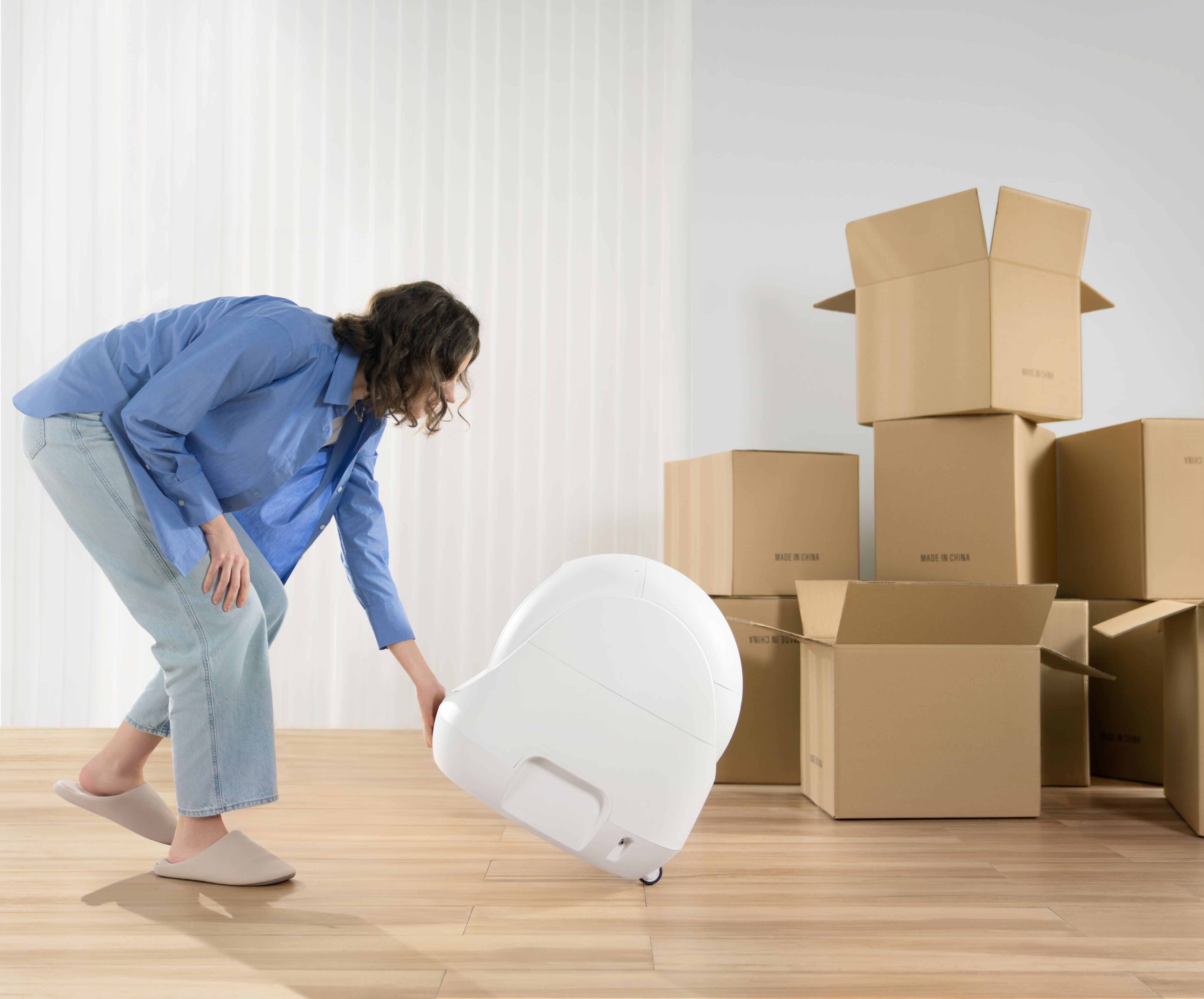 Person moving a white moving machine, with cardboard boxes in the background.