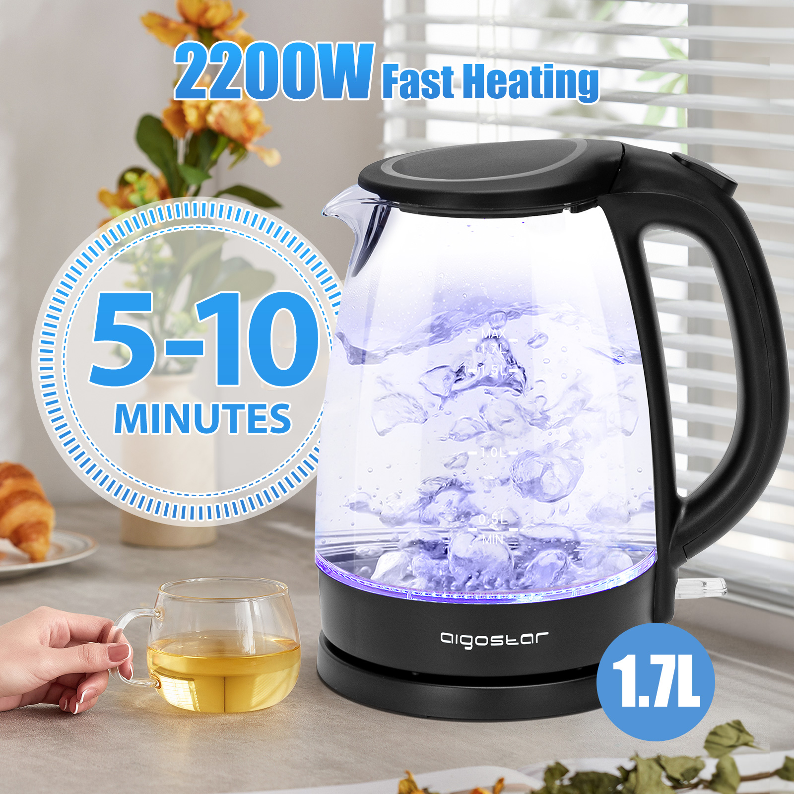 Hervidor eléctrico negro y vidrio con luces azules hirviendo agua, taza y cruasán al lado.