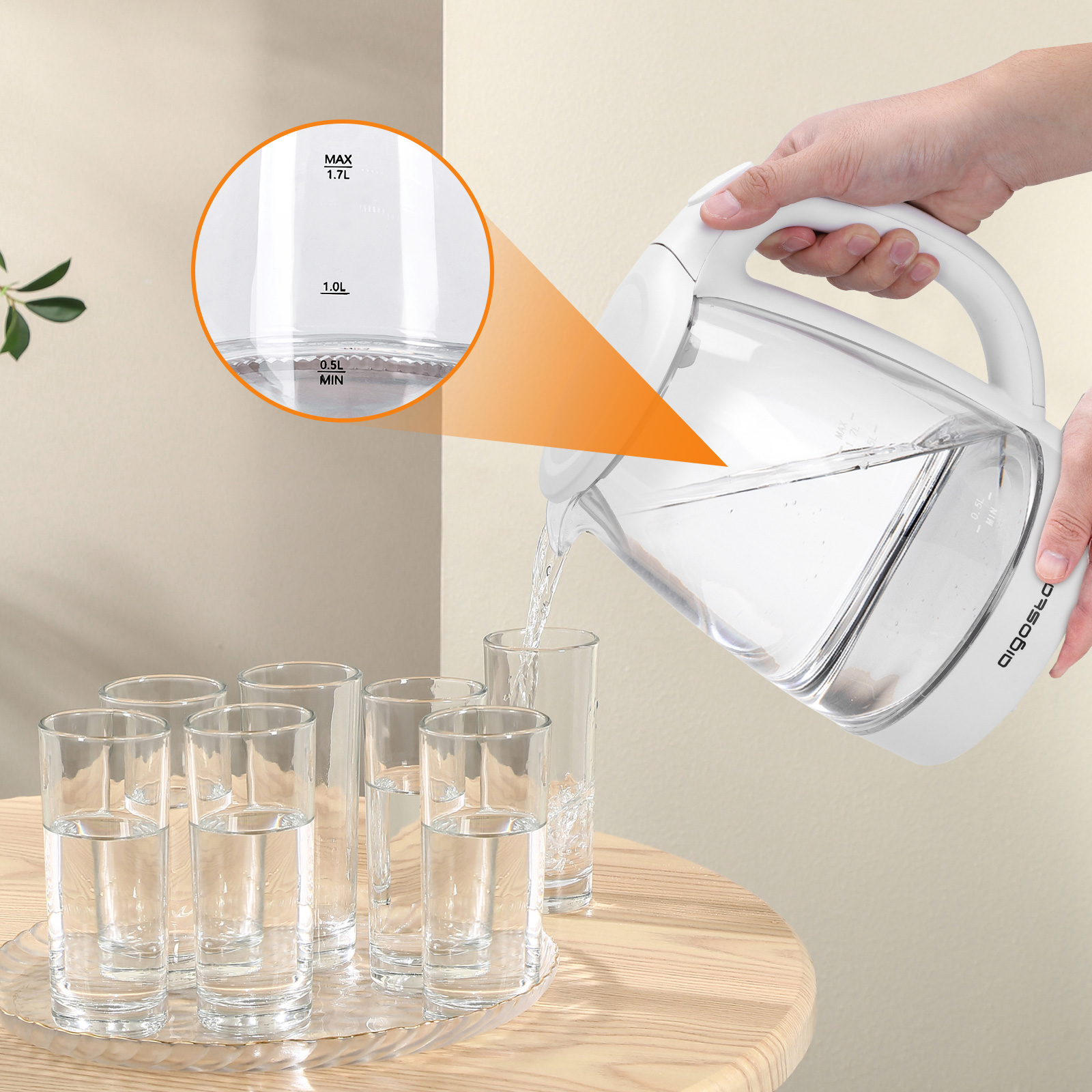 Una persona vierte agua de una jarra blanca en vasos. Hay una bandeja de vidrio y una mesa de madera.