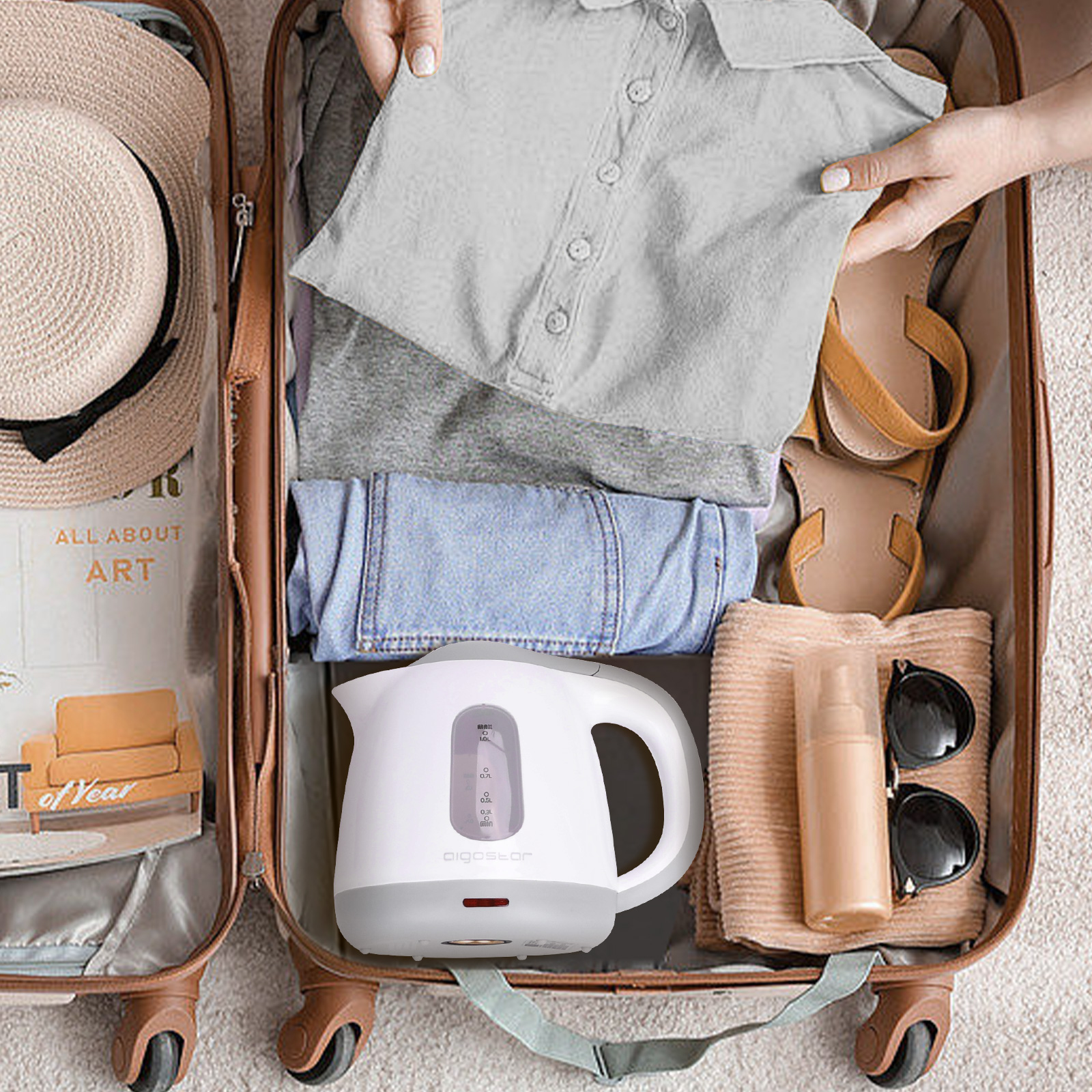 Offener Koffer mit Kleidung, Schuhen und einem weißen Wasserkocher. Packen für eine Reise.