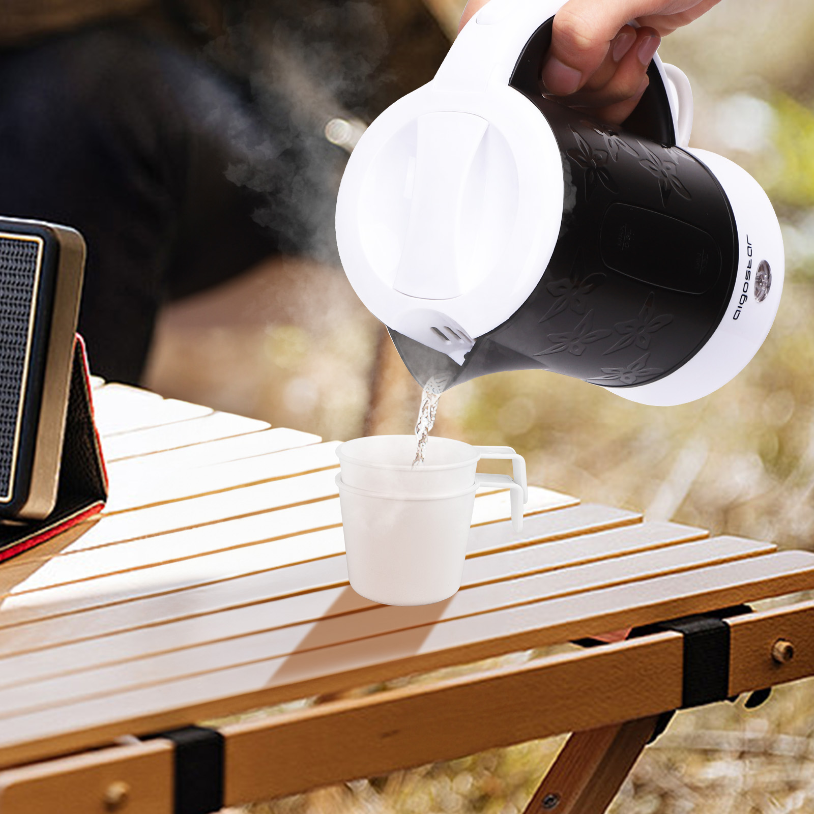 Hervidor eléctrico blanco y negro vertiendo agua en una taza.