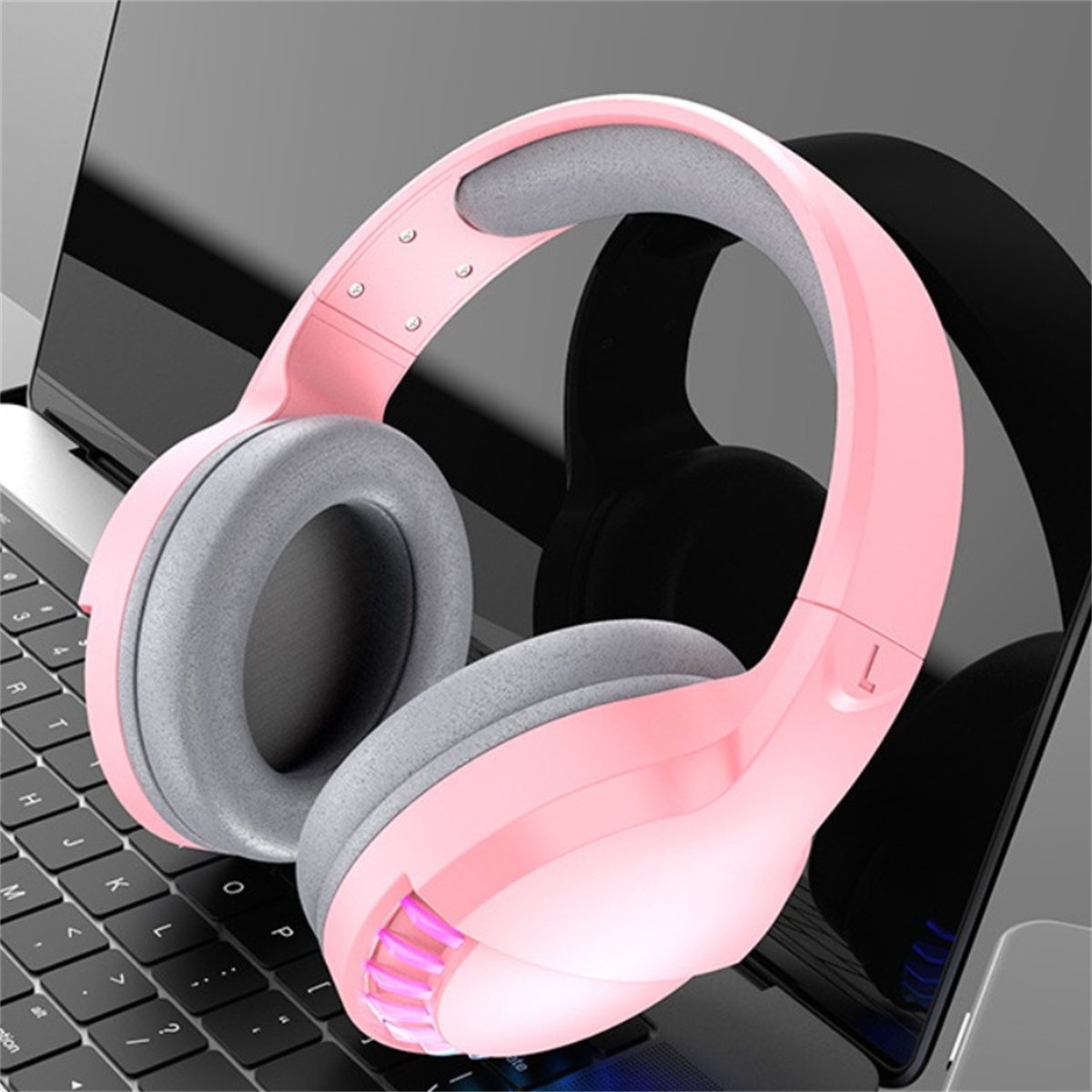 Pinke Gaming-Kopfhörer auf einer Laptop-Tastatur. Die Kopfhörer sind übergroß und leuchtend pink.