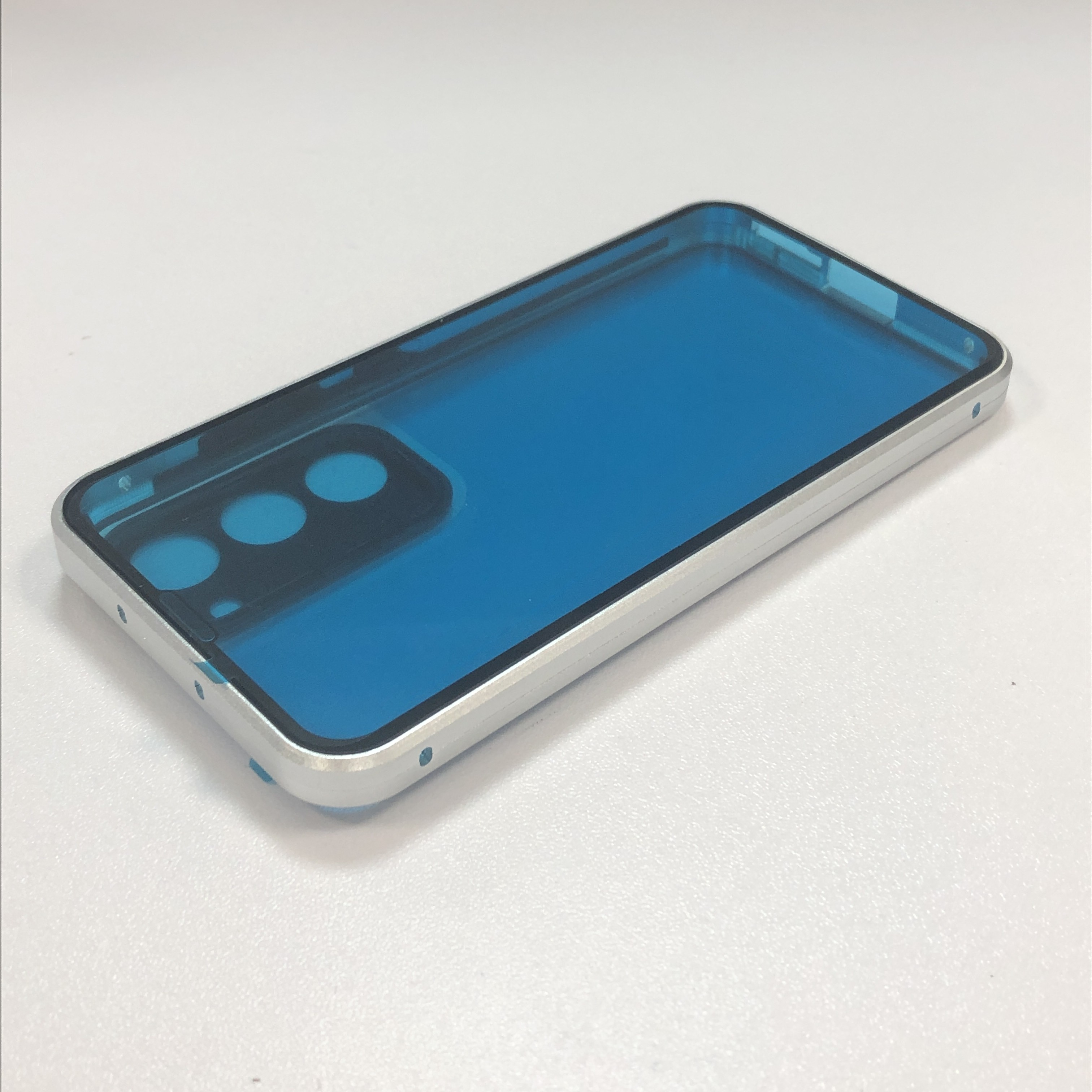 Eine Handyhülle mit silbernem Rahmen und blauem Innenraum liegt auf einer weißen Oberfläche.