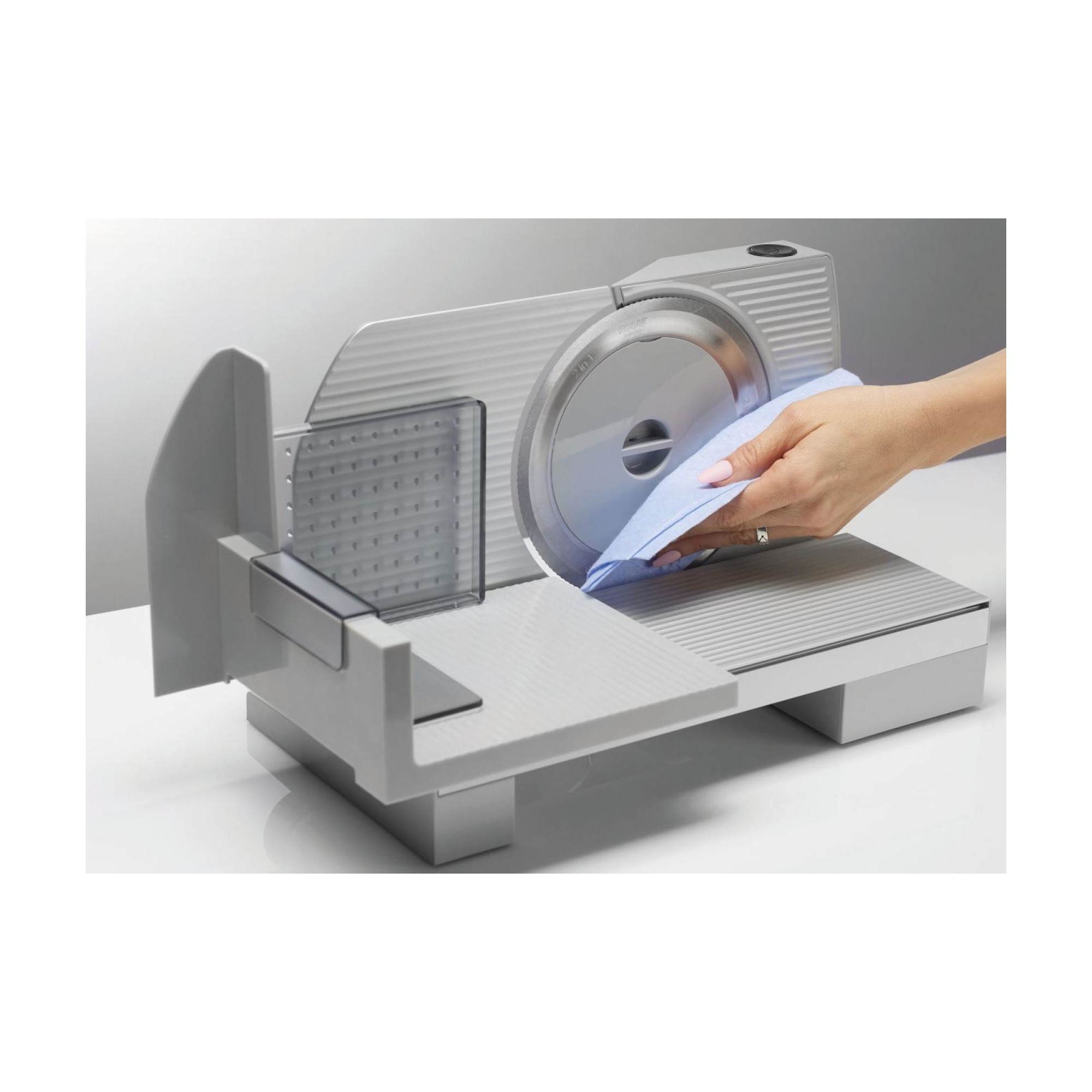 Kobieta używająca krajalnicy z niebieskim ręcznikiem na białej powierzchni.