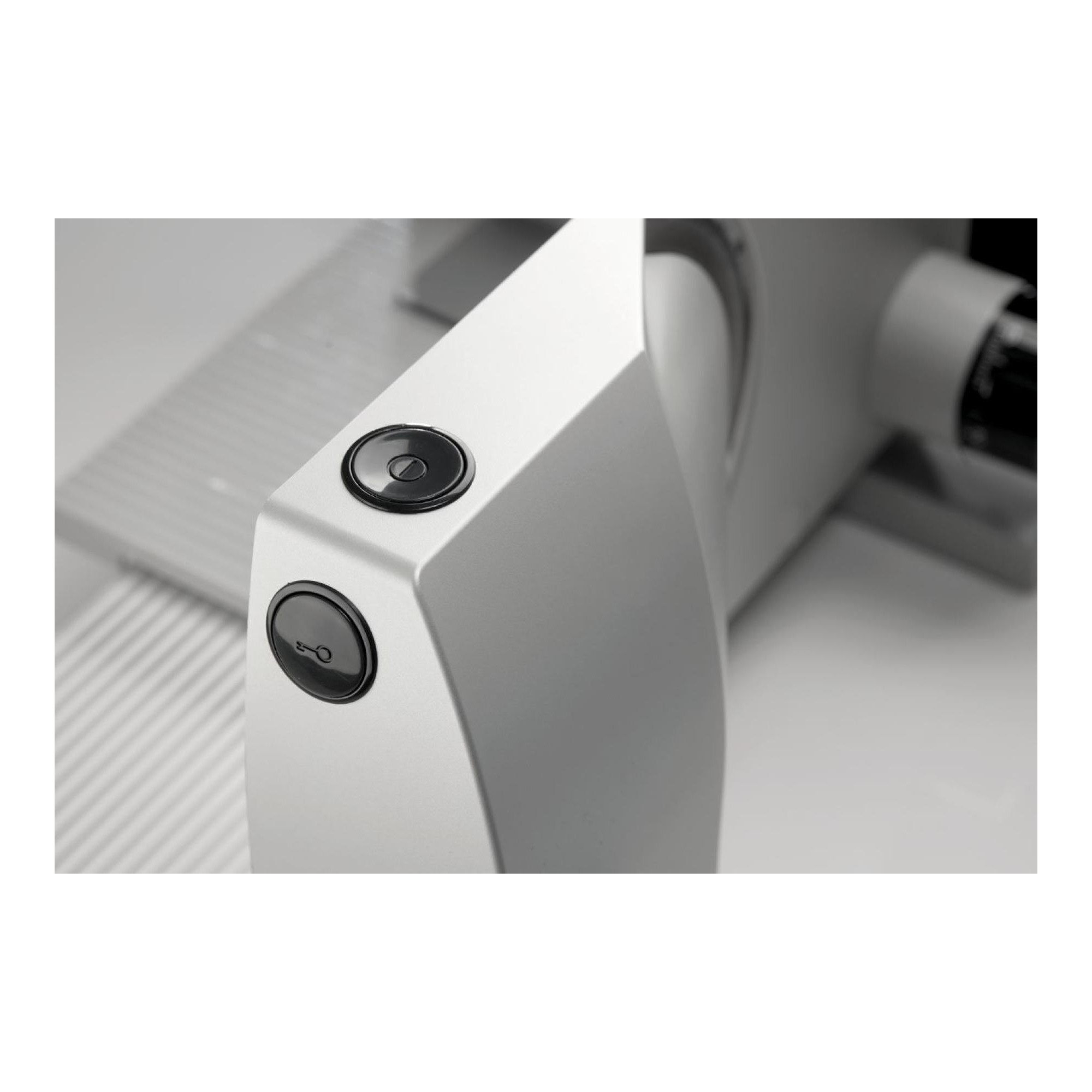 Zbliżenie srebrnej krajalnicy do żywności z czarnymi przyciskami i białą powierzchnią.