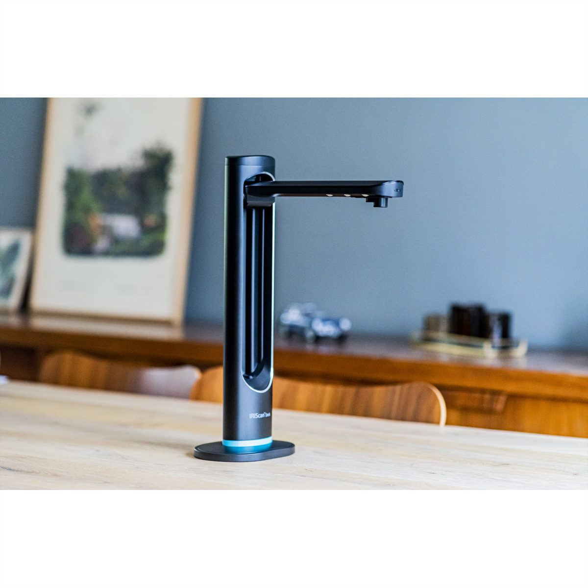 Escáner vertical con cuerpo negro y base blanca, aislado sobre una mesa.