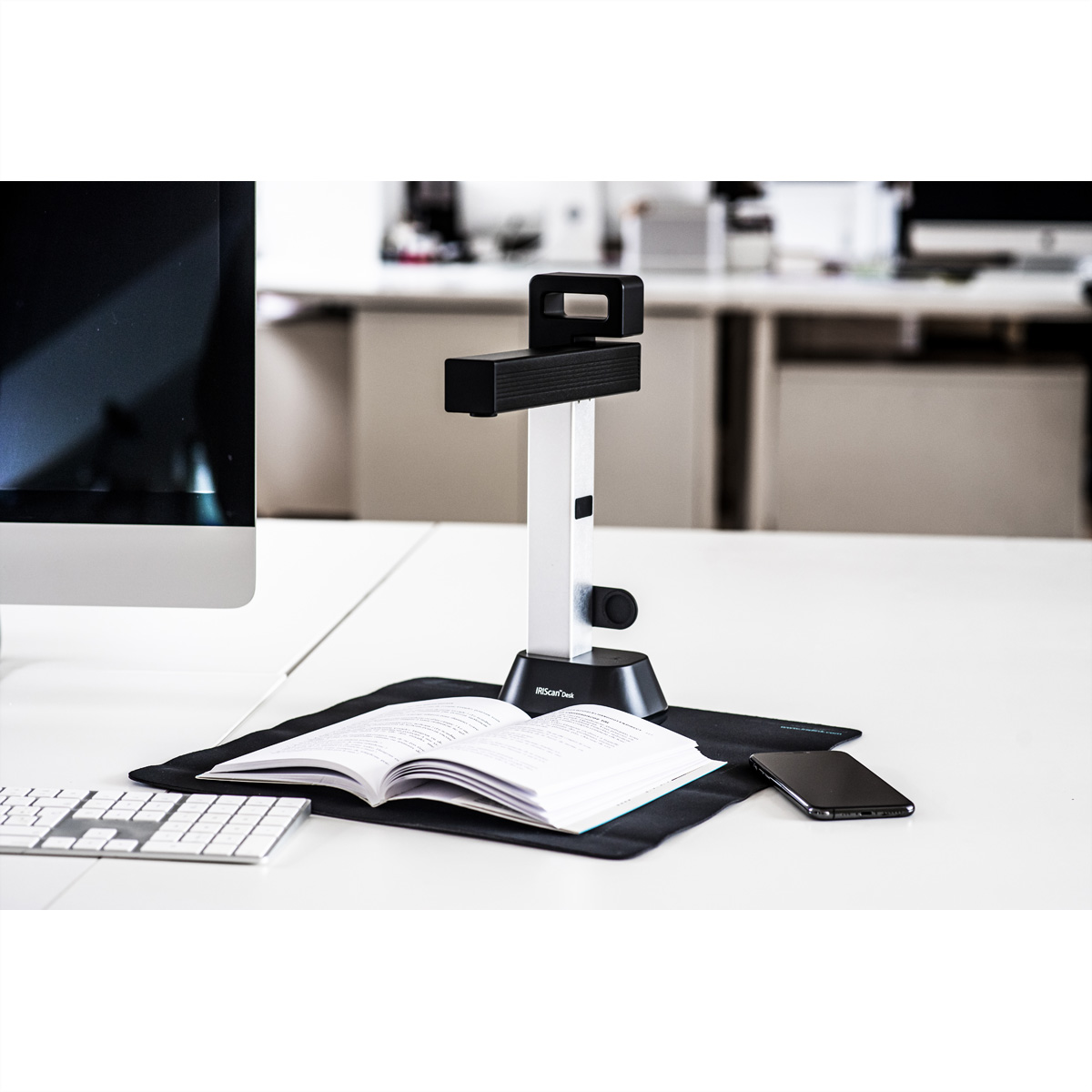Scanner per documenti su una scrivania con un libro e uno smartphone.
