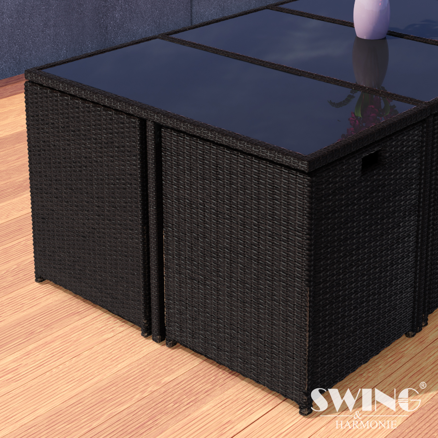Schwarzer Outdoor-Tisch und -Stühle aus Korbgeflecht. Glasplatte, auf Holzboden. Swing & Harmonie Logo sichtbar.