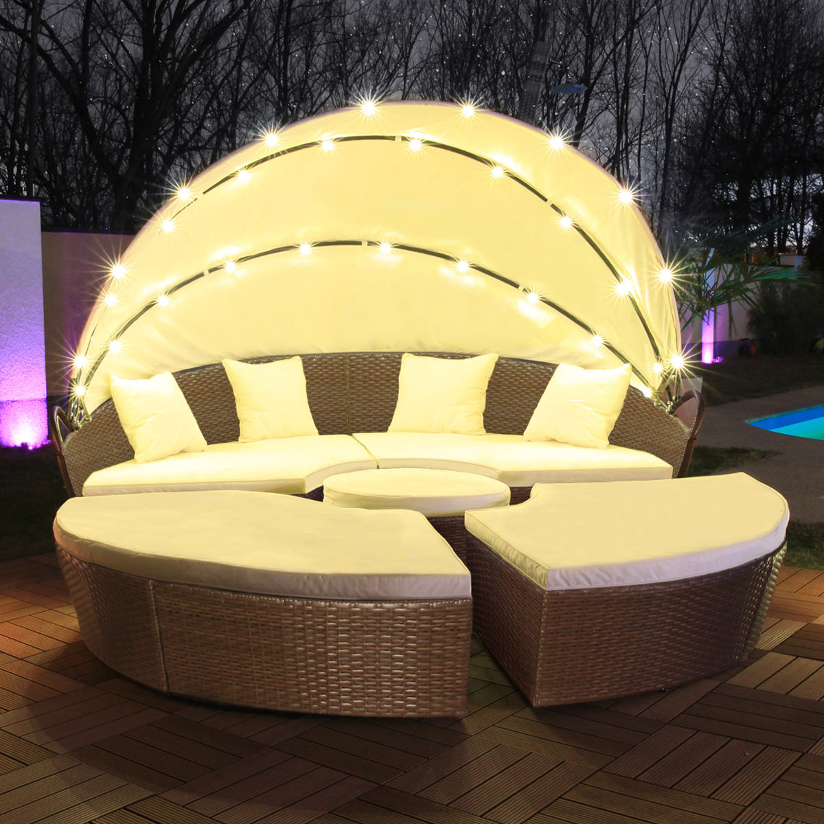 Outdoor-Sitzgruppe mit geschwungenem Sofa, rundem Tisch und zwei geschwungenen Hockern, mit Lichtern.