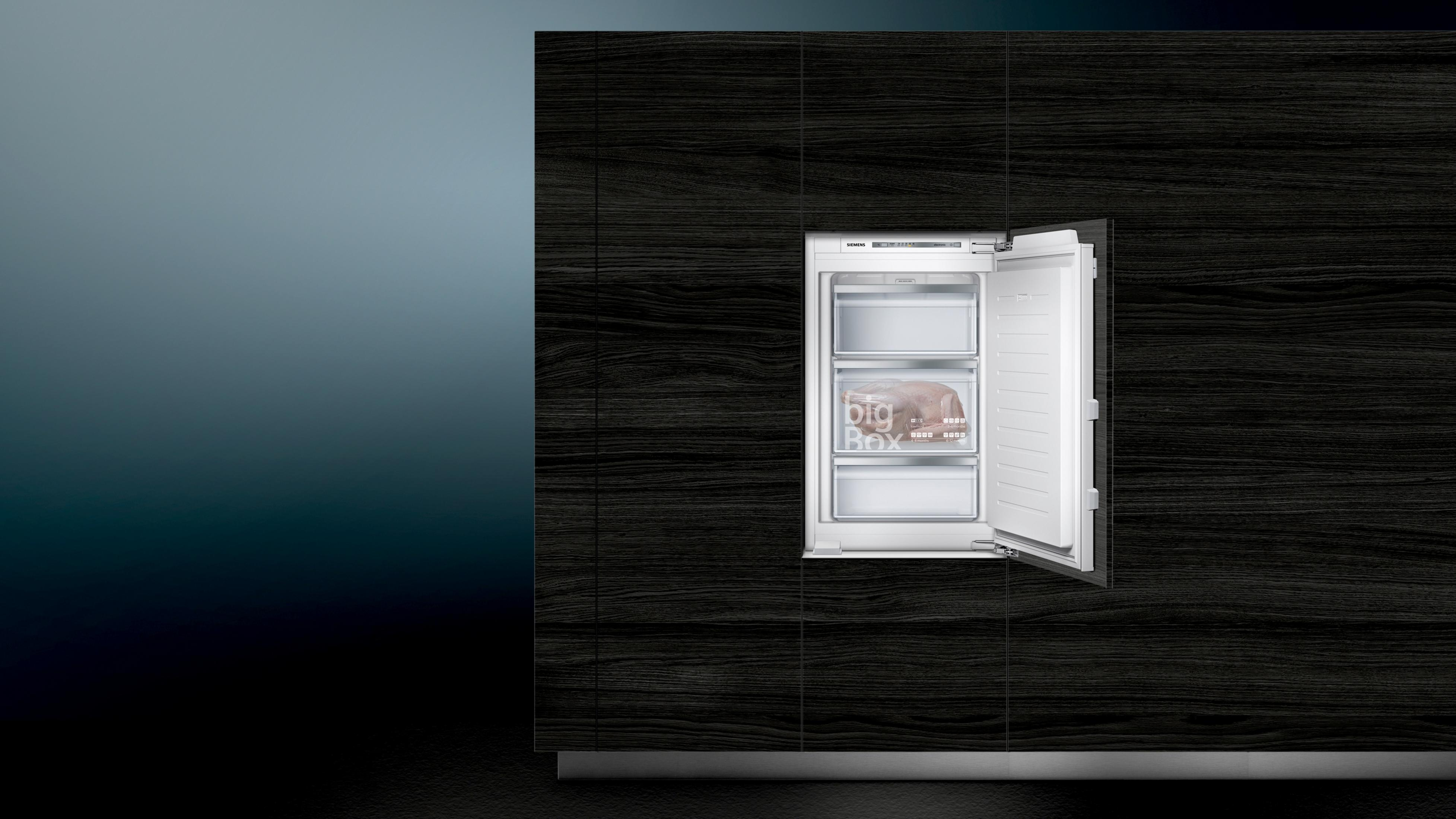 Einbaukühlschrank, Tür offen mit Regalen mit Lebensmitteln. Dunkle Holzverkleidung im Hintergrund.