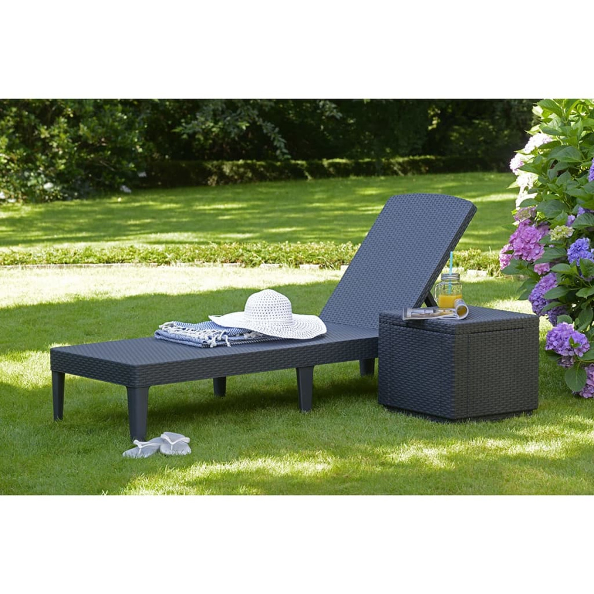Una moderna chaise longue nera con un tavolino in un giardino.