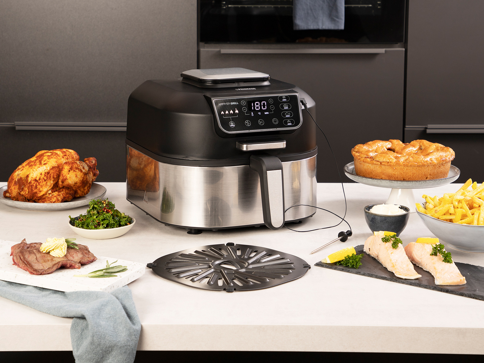 Czarna i srebrna frytownica powietrzna z ugotowanym jedzeniem i akcesoriami.