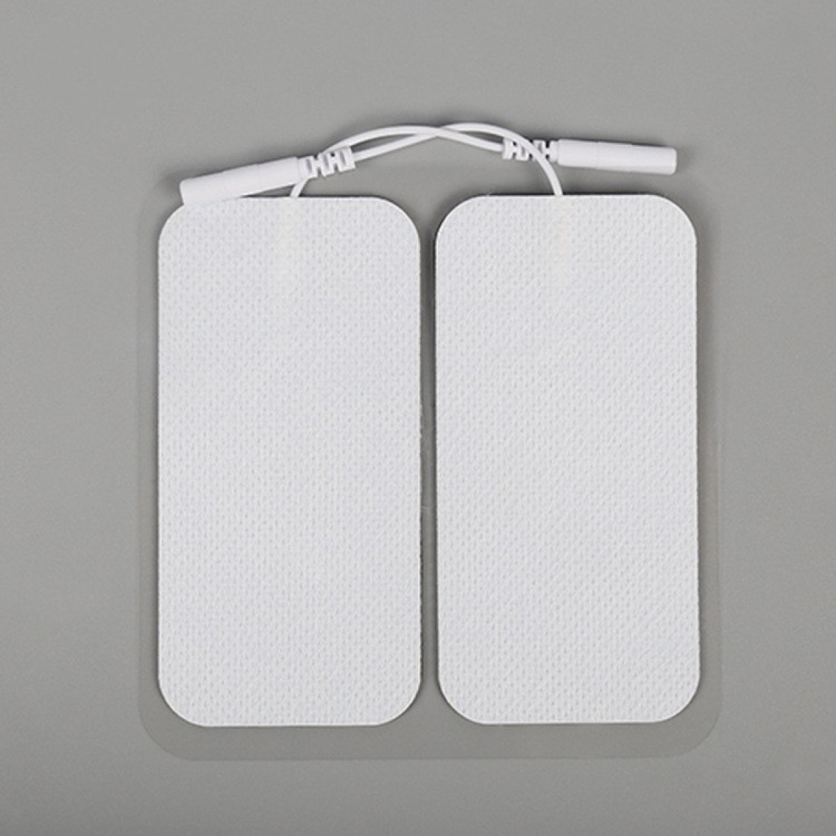 Zwei weiße Elektrodenpads, verbunden durch Drähte, auf grauem Hintergrund.