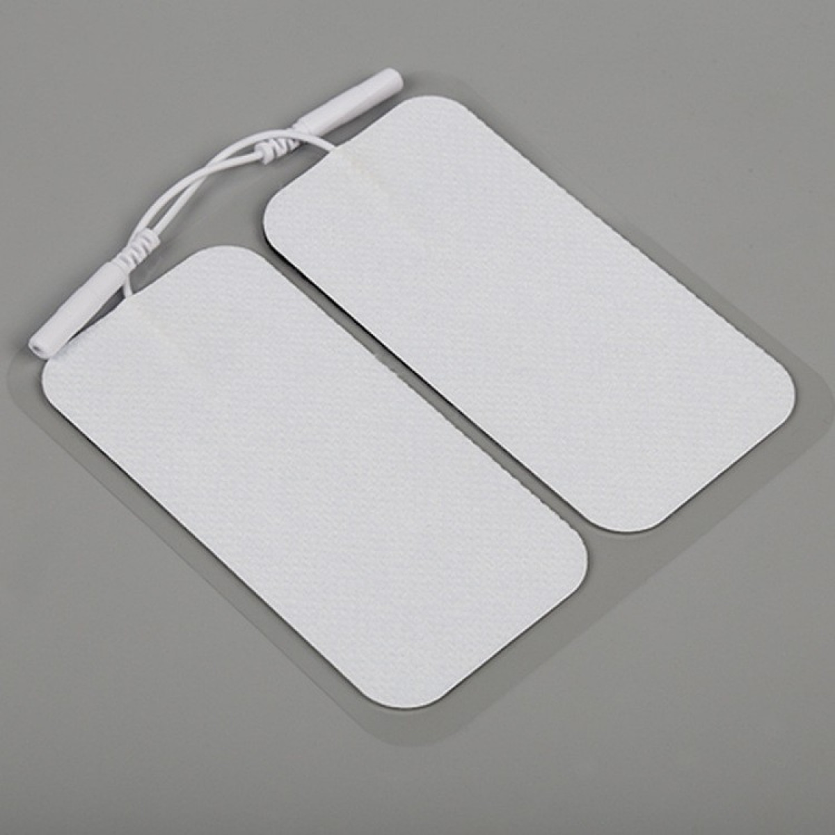 Zwei weiße, rechteckige Elektrodenpads, die durch einen weißen Draht mit einem Stecker verbunden sind.