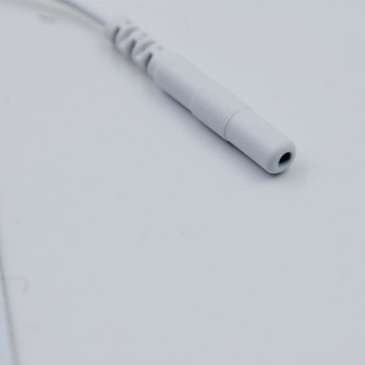 Weißer Stecker mit abgerundeter Spitze, Nahaufnahme vor weißem Hintergrund.