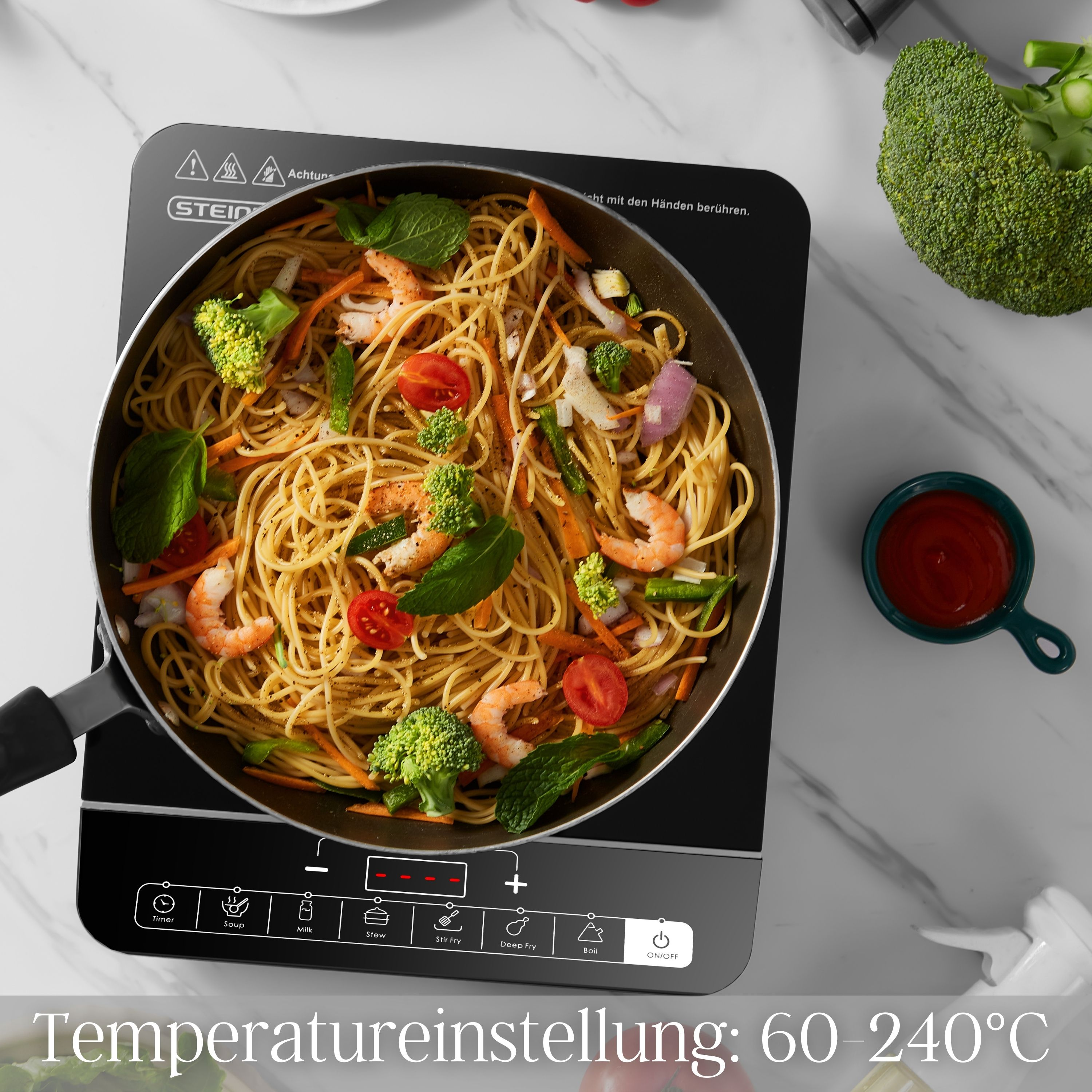 Kochen auf einem Induktionskochfeld. Spaghetti mit Garnelen und Gemüse in einer Pfanne.