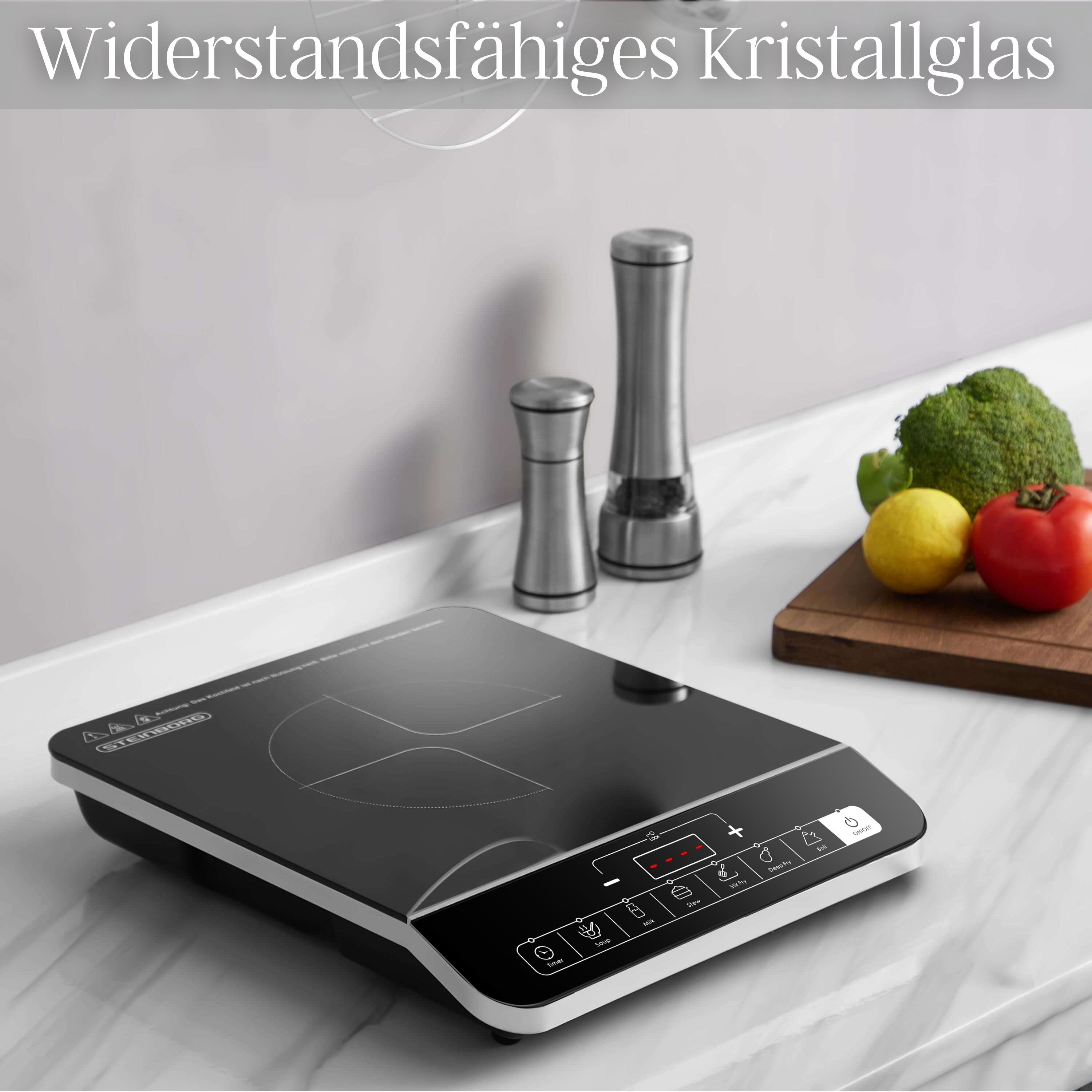 Schwarzes Induktionskochfeld mit Gemüse. Zwei silberne Shaker und Holzbrett.
