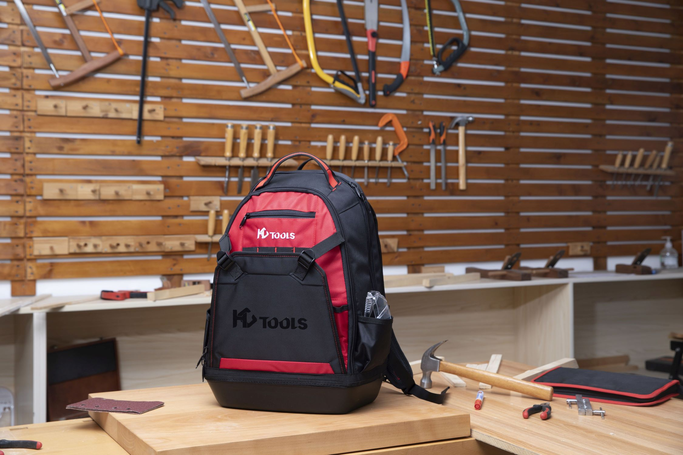 Ein KD Tools Rucksack auf einem Holztisch mit Werkzeugen in einer Werkstatt.