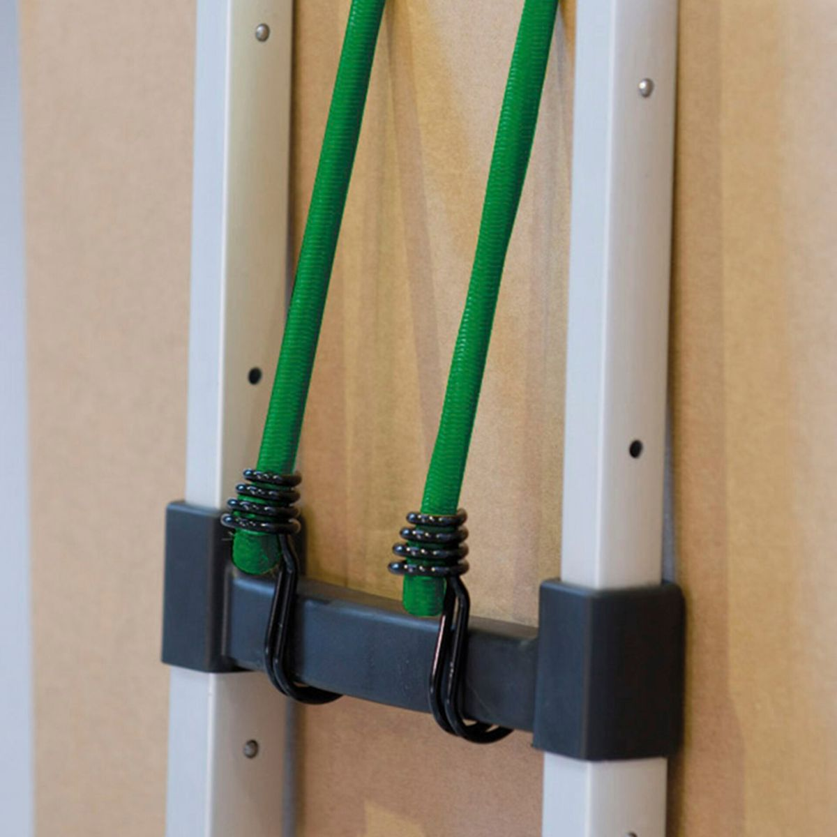 Corde elastiche verdi con ganci, attaccate a un telaio bianco e nero, primo piano.