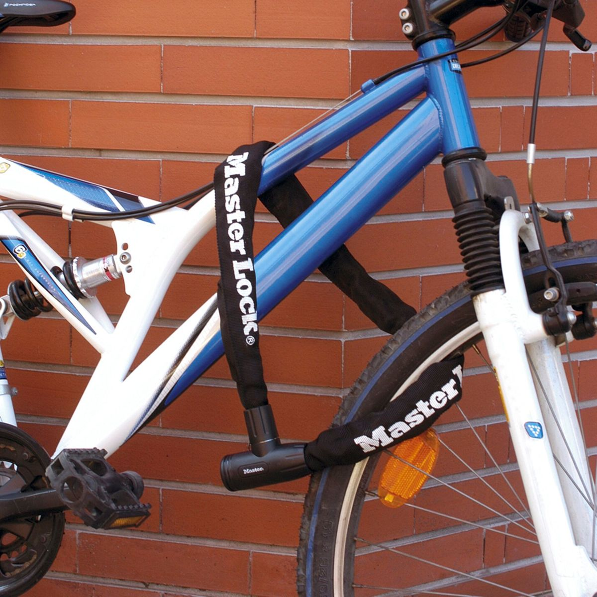 Una bicicletta assicurata con un lucchetto a catena Master Lock avvolto attorno al telaio e un muro di mattoni.