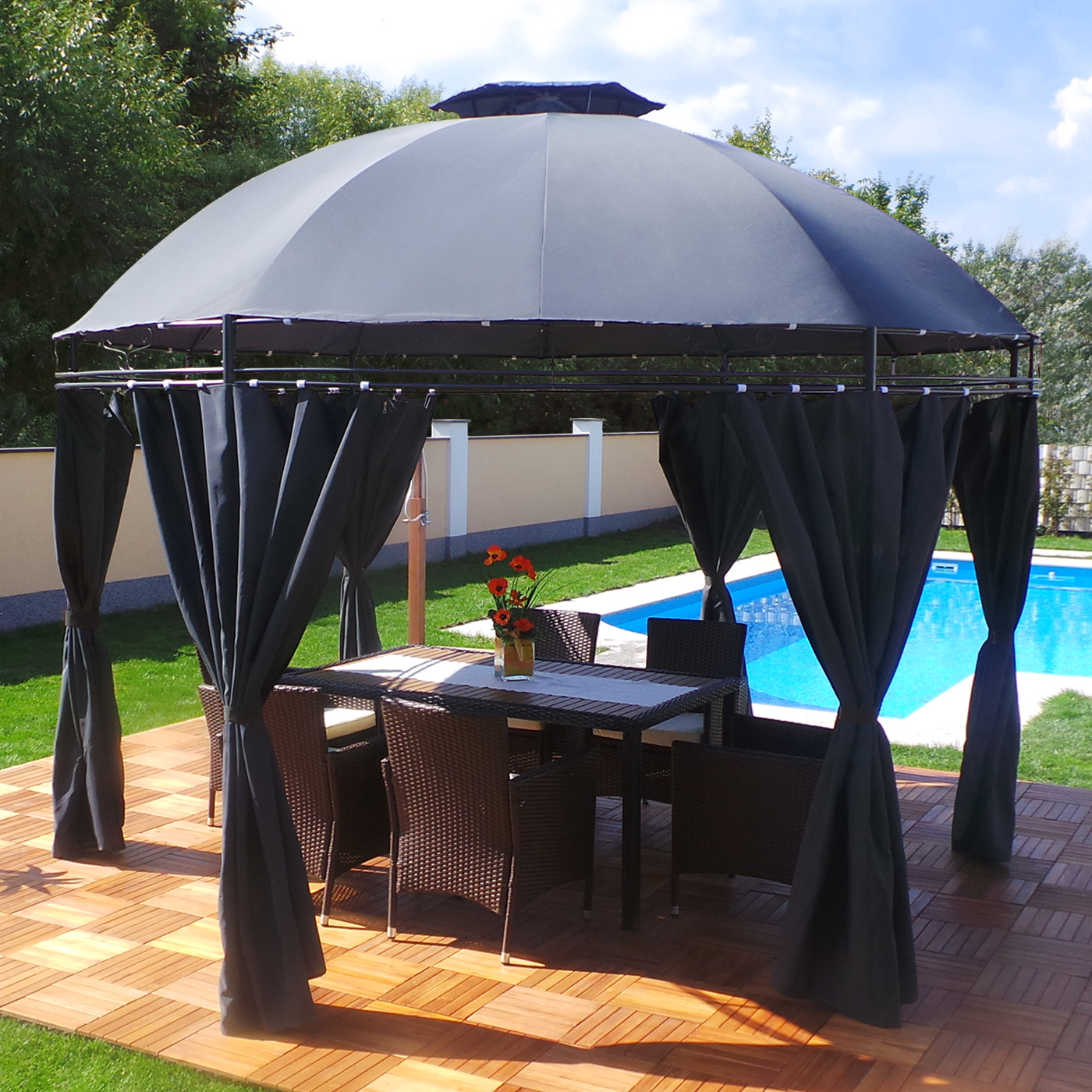 Ein Outdoor-Pavillon mit schwarzen Vorhängen, einem Tisch, Stühlen und einem Pool im Hintergrund.
