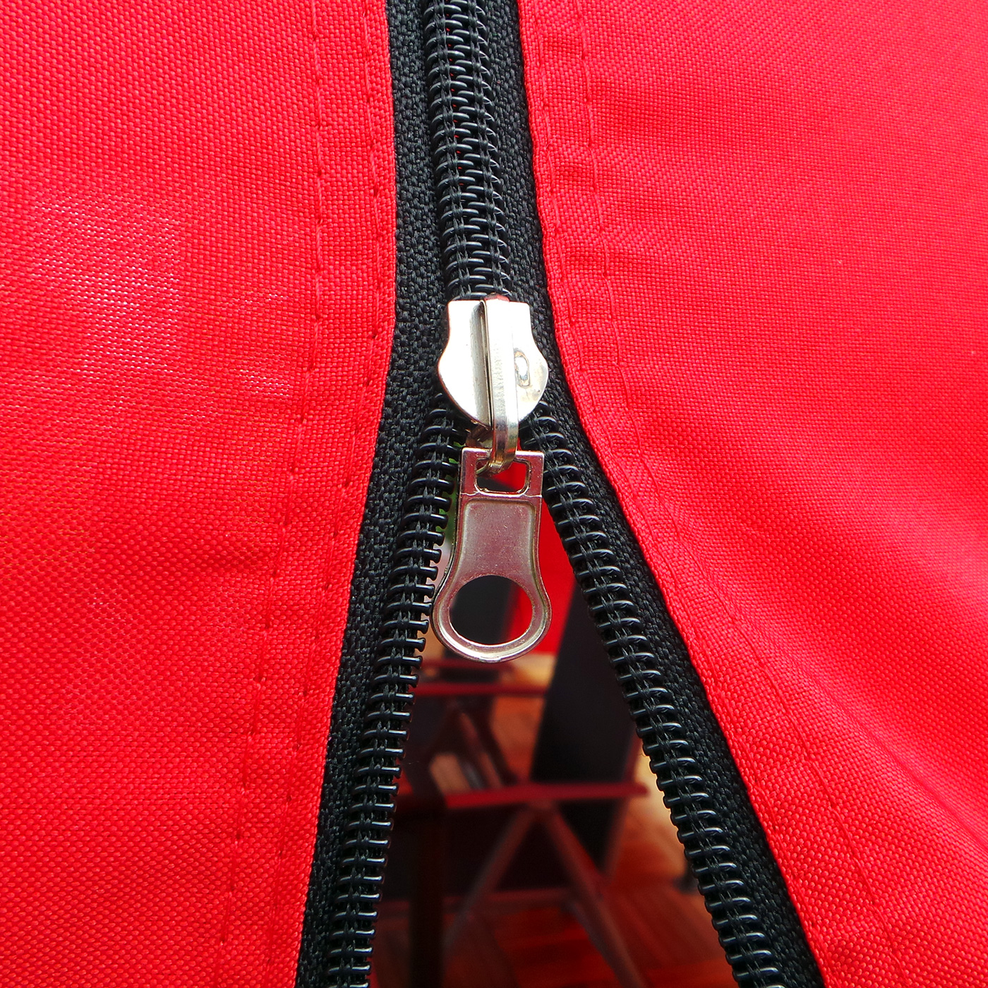 Roter Stoff mit schwarzem Reißverschluss. Der Reißverschluss ist offen. Nahaufnahme.
