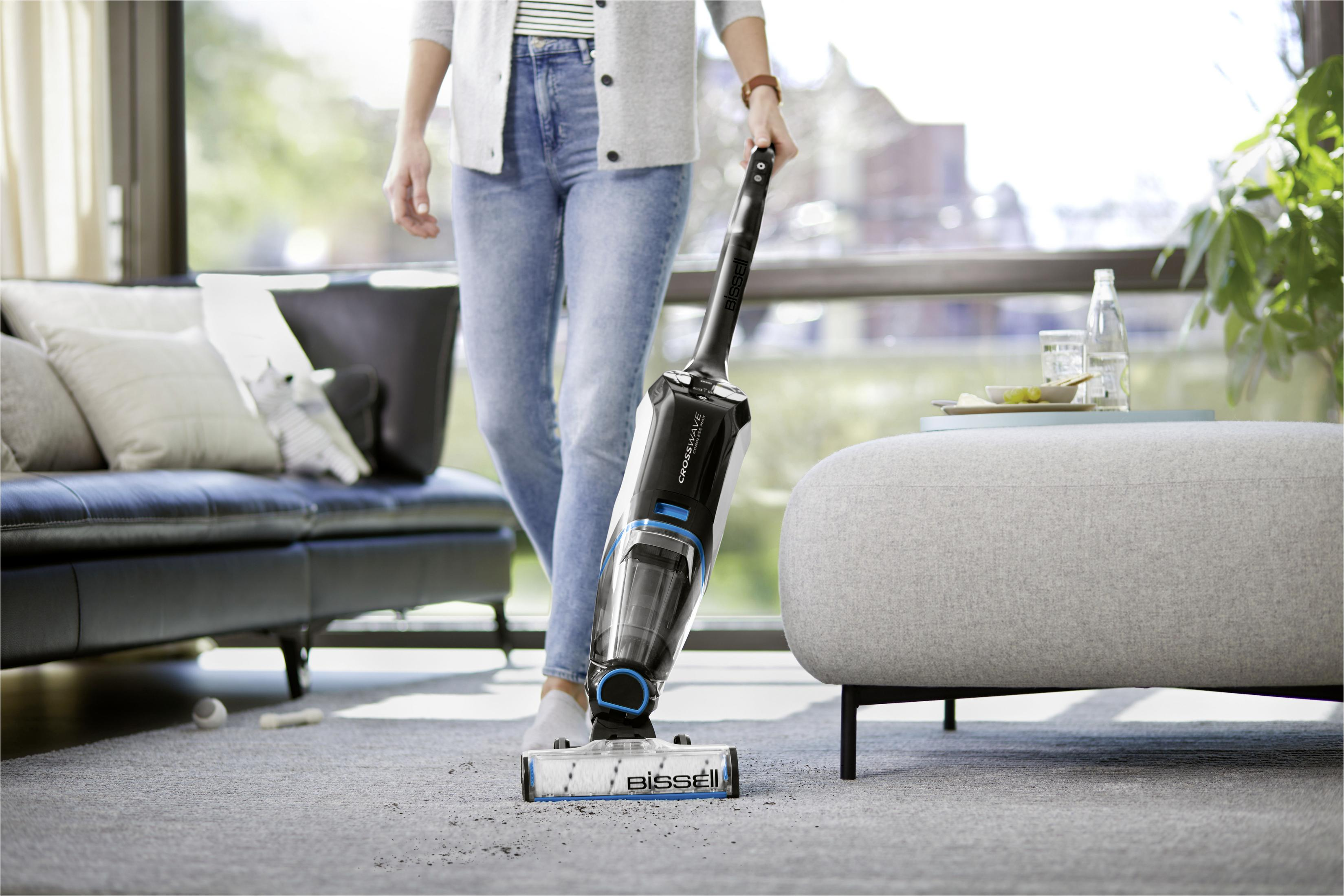 Una persona che aspira un tappeto con un pulitore Bissell CrossWave.