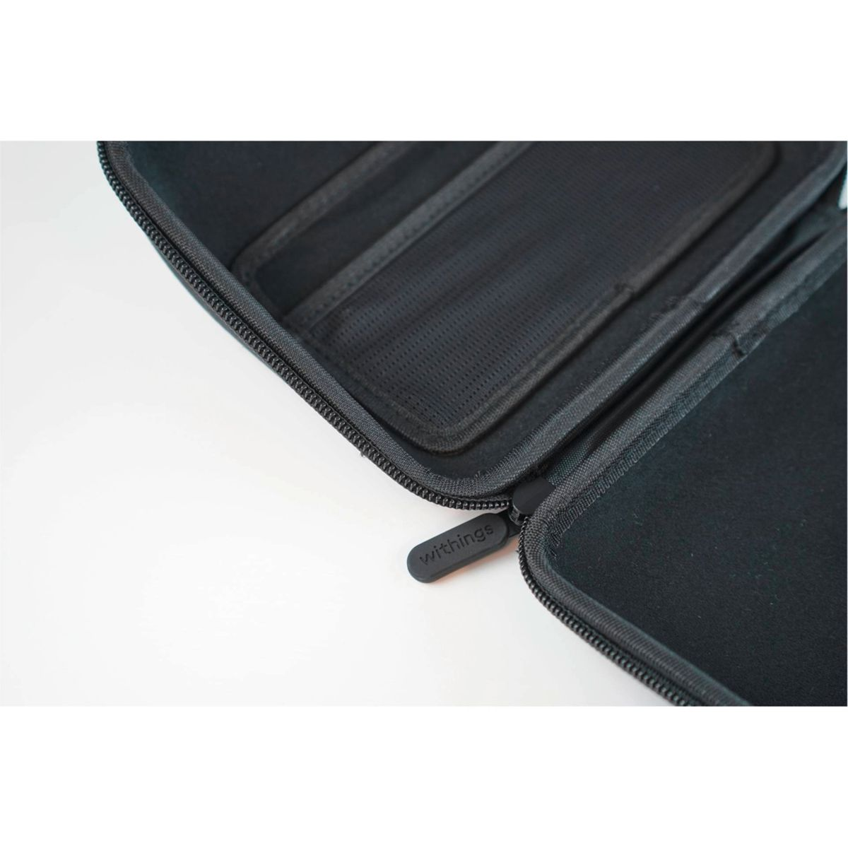 Schwarzes Etui mit Reißverschluss offen, mit dem Wort 'withings' am Reißverschluss.