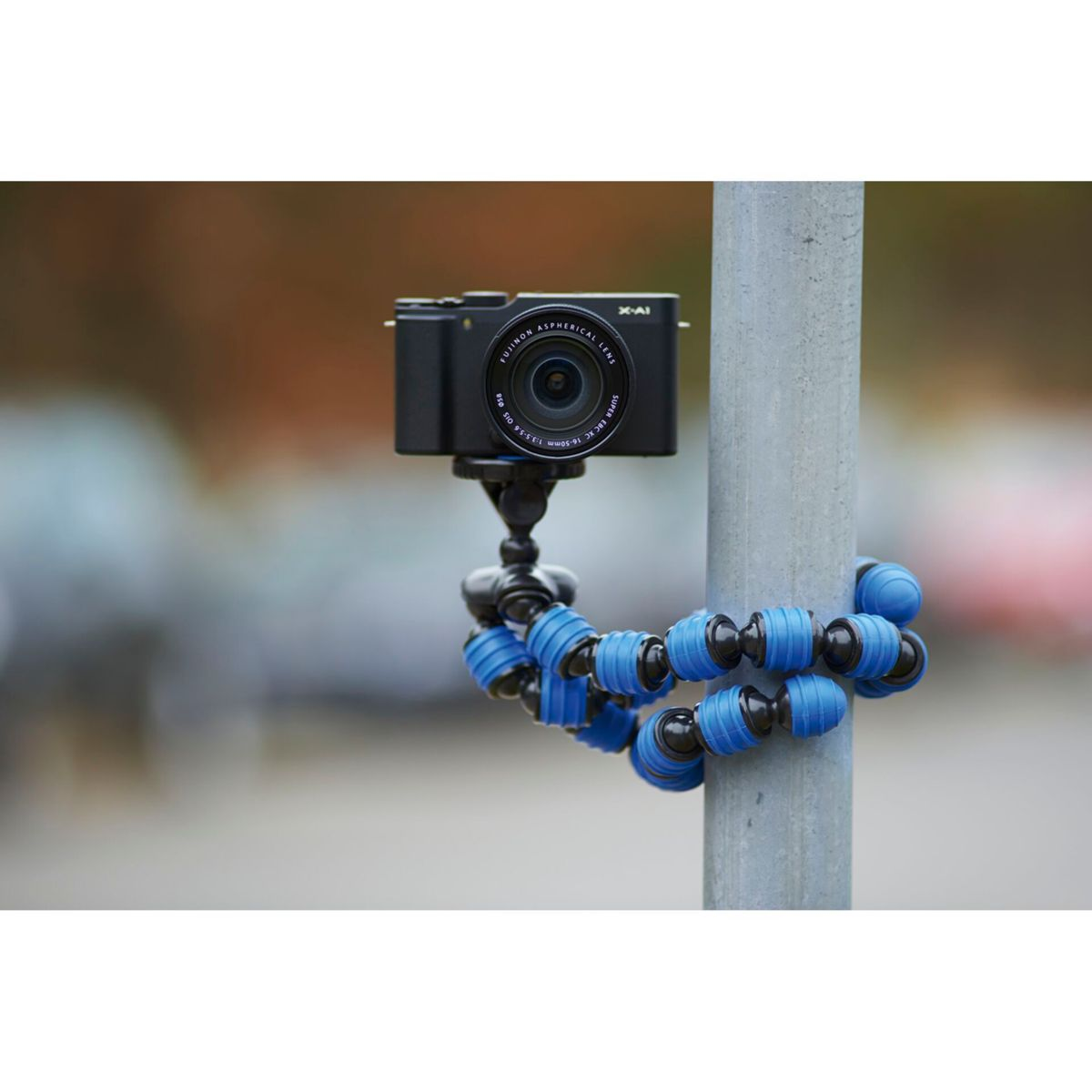 Czarny aparat zamontowany na elastycznym niebiesko-czarnym statywie przymocowanym do słupa.