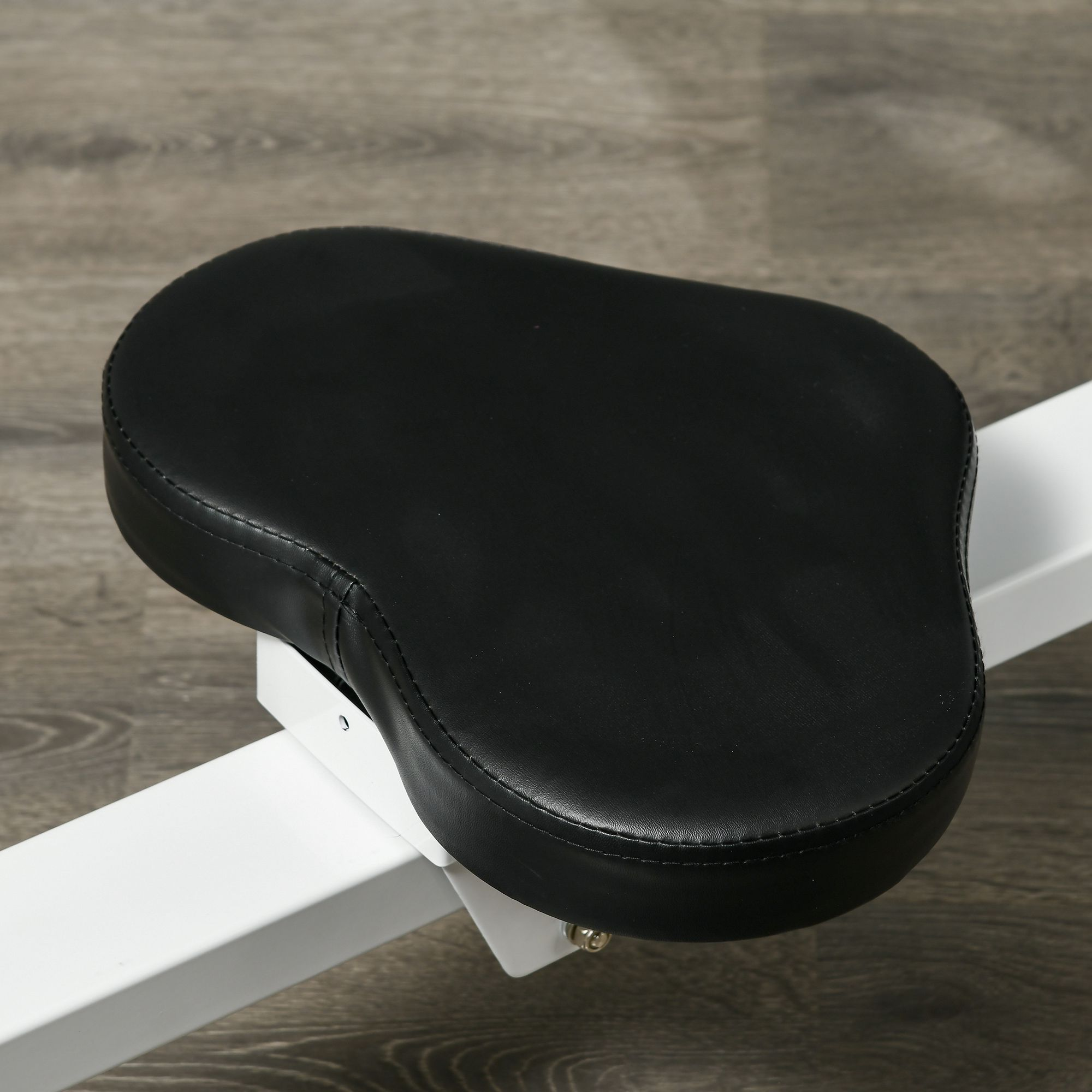 Asiento negro, similar al cuero, de forma ovalada sobre un marco blanco.