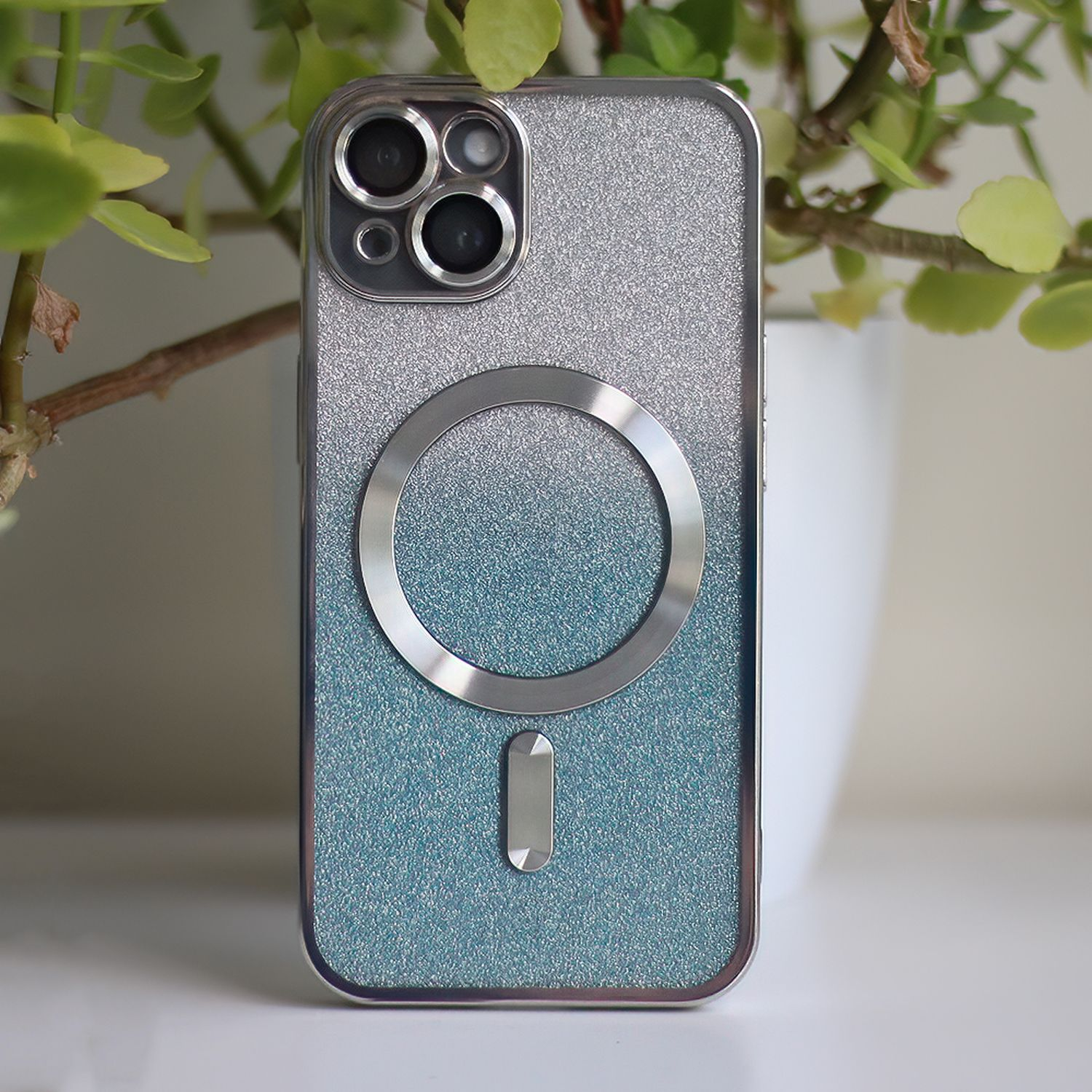 Custodia per telefono con glitter e anello magnetico. Pianta verde sullo sfondo.