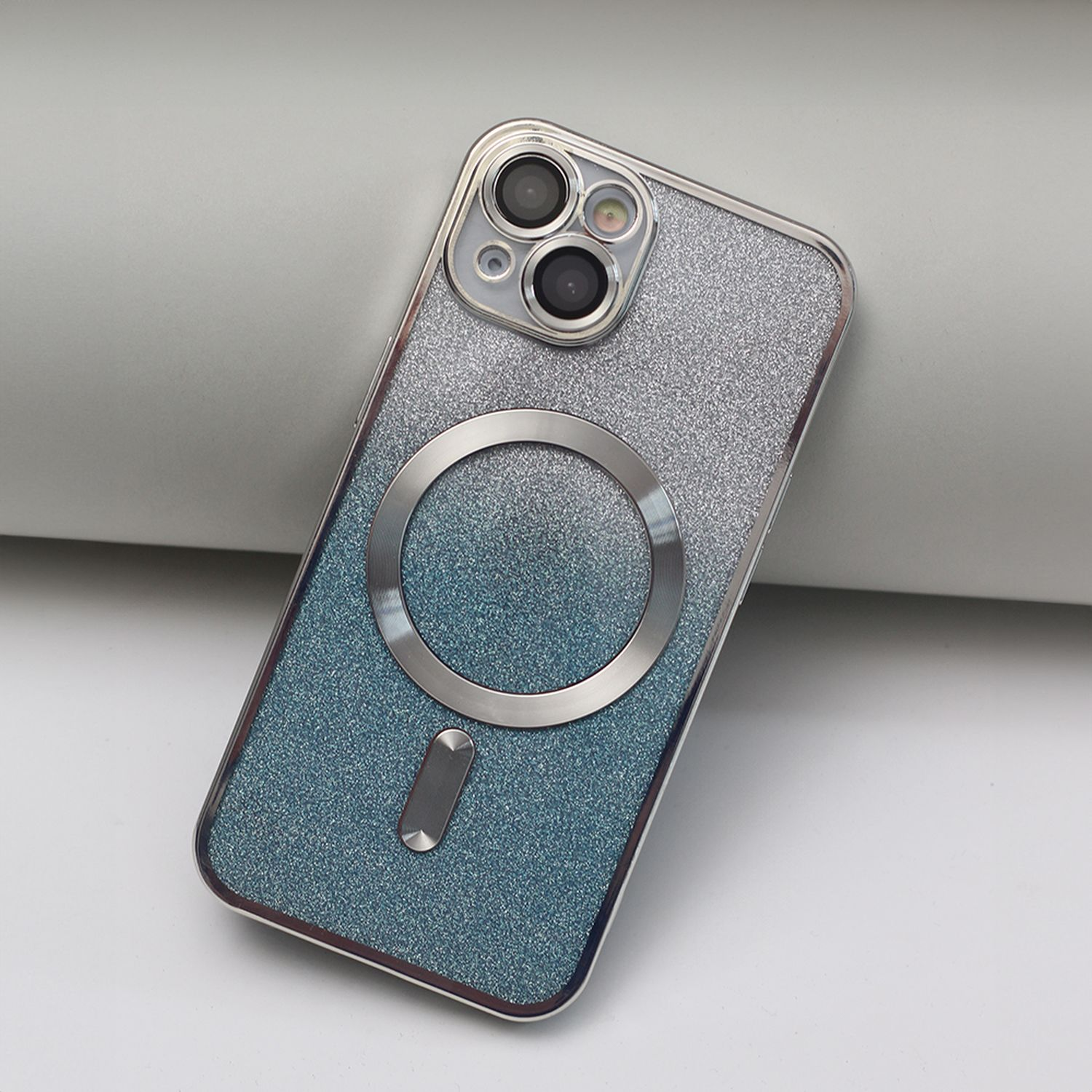 Una custodia per telefono, con cornice argentata e retro blu glitterato, e un dettaglio circolare argentato.