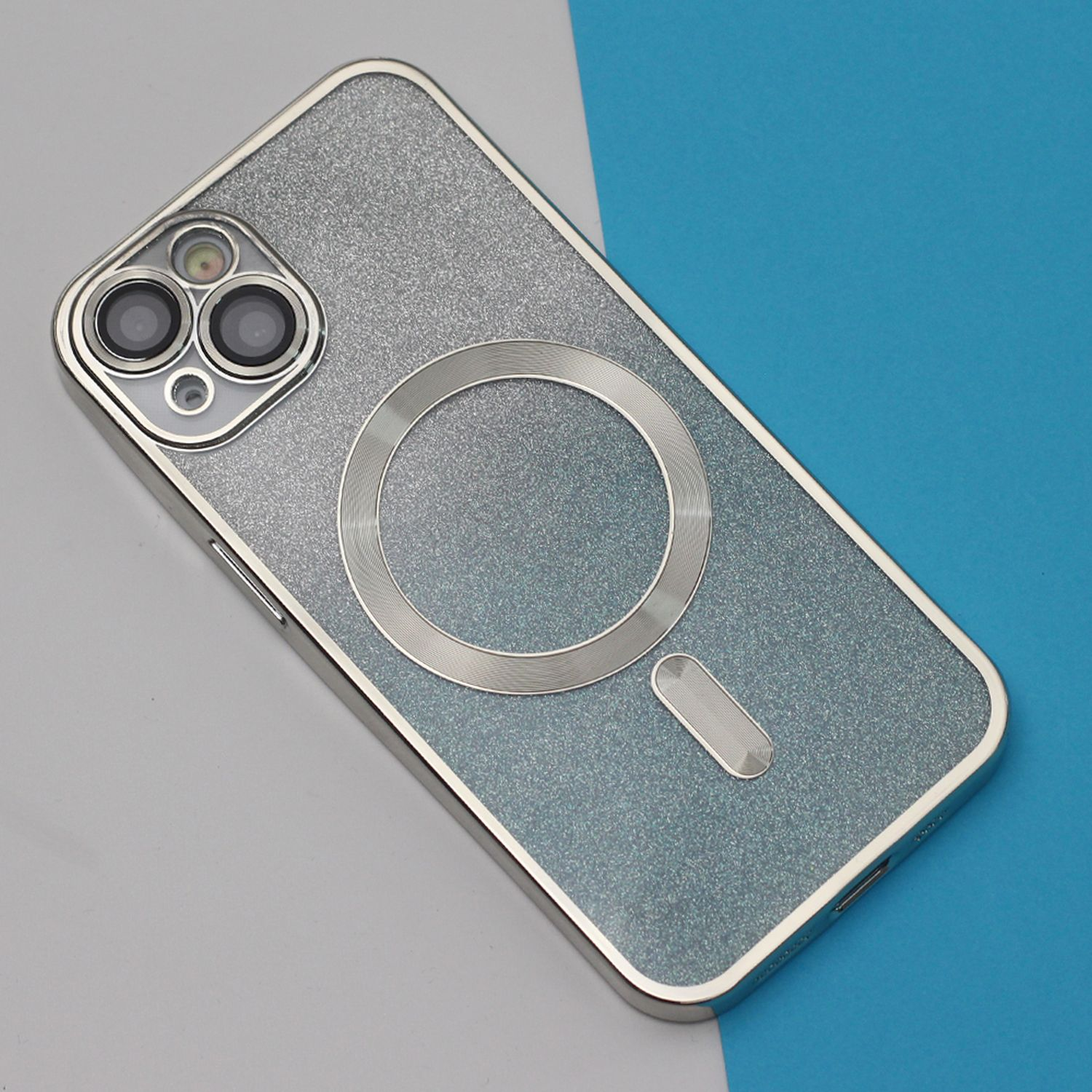 Una custodia per telefono argentata con un cerchio metallico e obiettivi della fotocamera. Lo sfondo è blu e grigio.