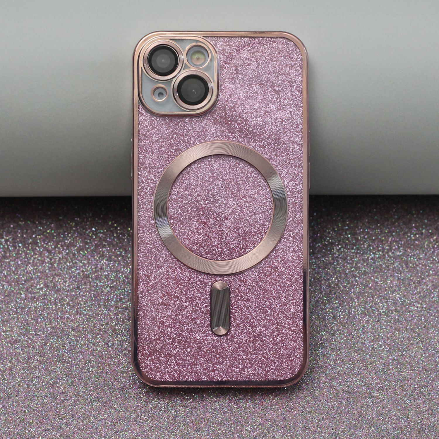 Primo piano di una custodia per telefono rosa glitterata con fotocamera e dettaglio ad anello magnetico.