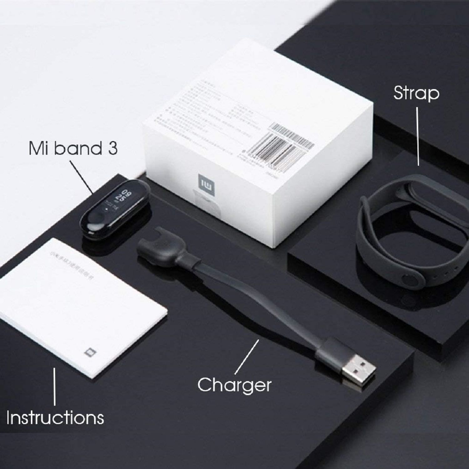 Mi Band 3, Armband, Ladegerät und Anweisungen auf schwarzen Plattformen. Oben befindet sich eine weiße Box.