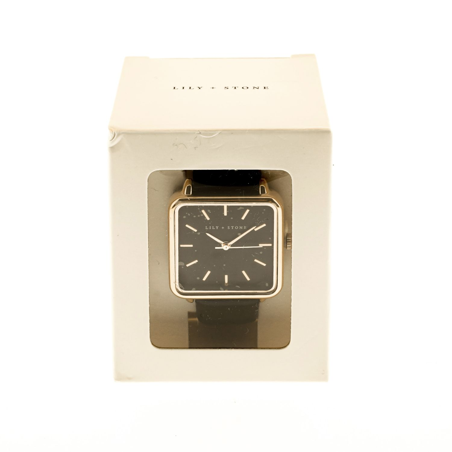 Eine quadratische schwarze Uhr in einer weißen Box. Die Uhr hat einen goldenen Rahmen und ein schwarzes Lederarmband.