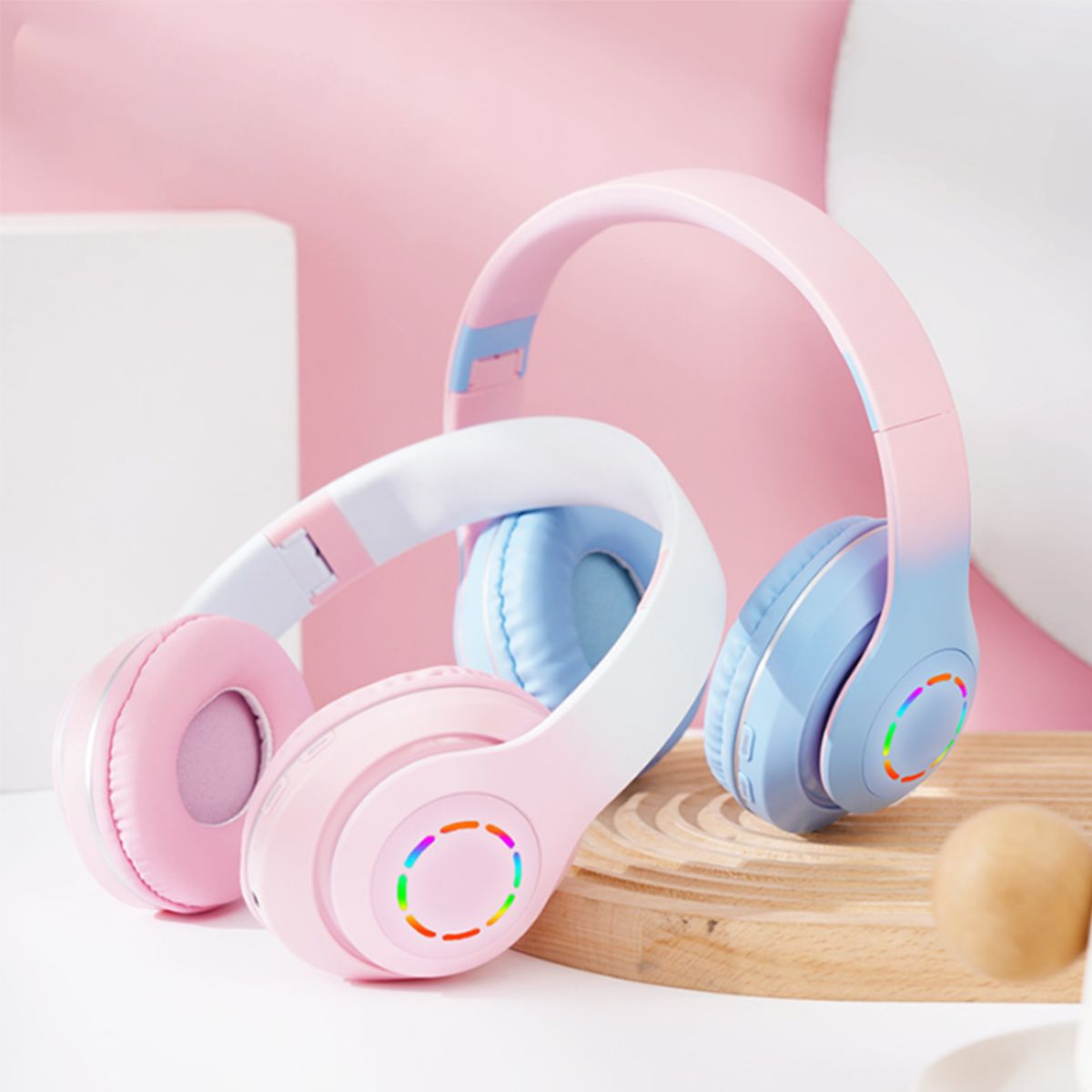Zwei Paare kabelloser Kopfhörer, rosa und blau, mit bunten Lichtakzenten.