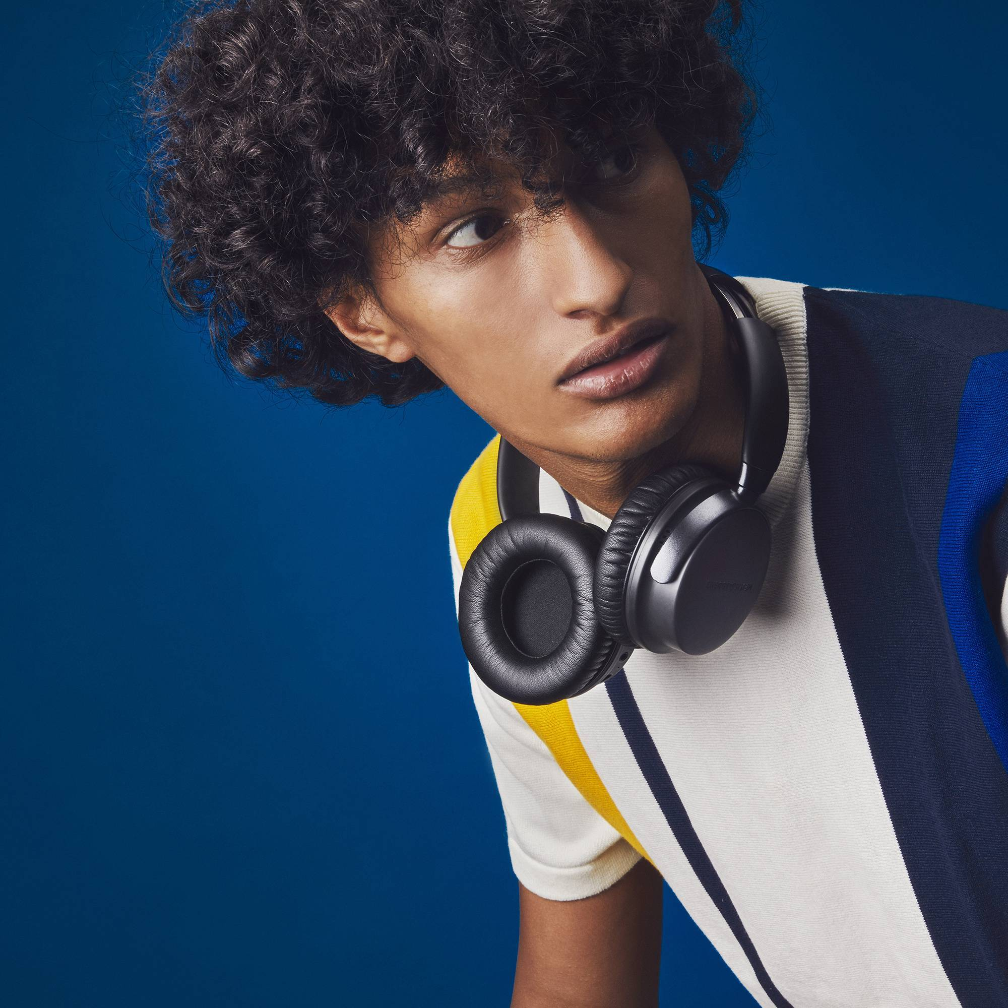 Mężczyzna w słuchawkach, odwrócony. Niebieskie tło.