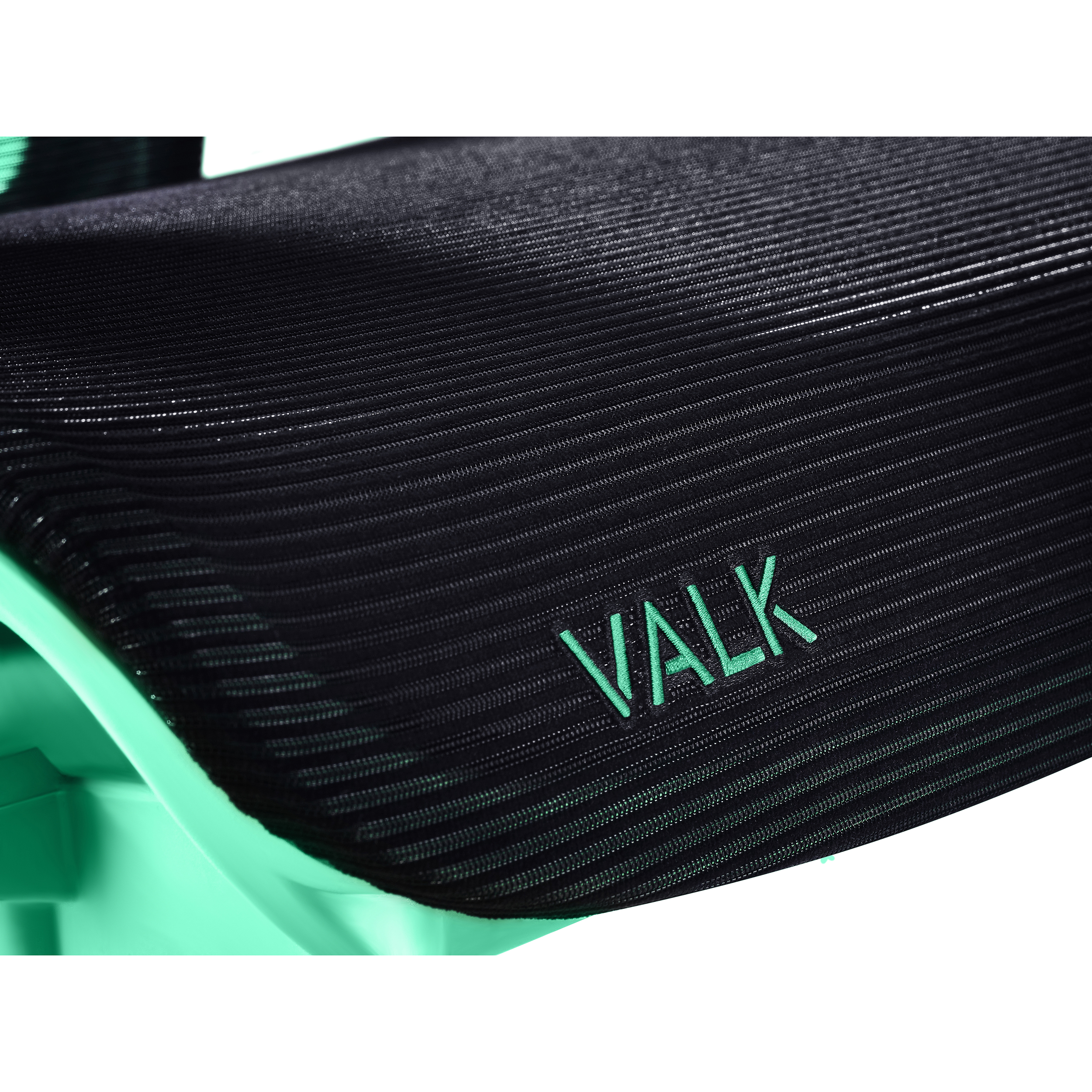 Primer plano del asiento de una silla de malla negra con la palabra VALK en verde azulado.