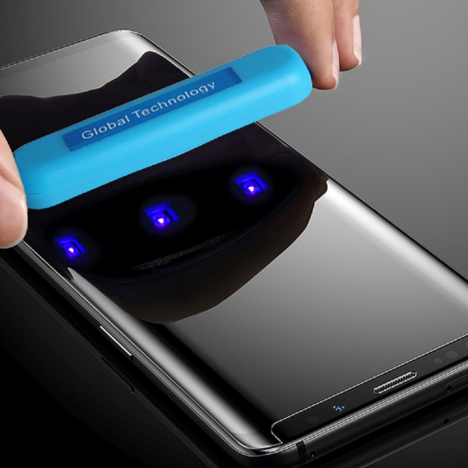 Hand, die UV-Licht verwendet, um den Displayschutz auf einem schwarzen Smartphone zu entfernen.
