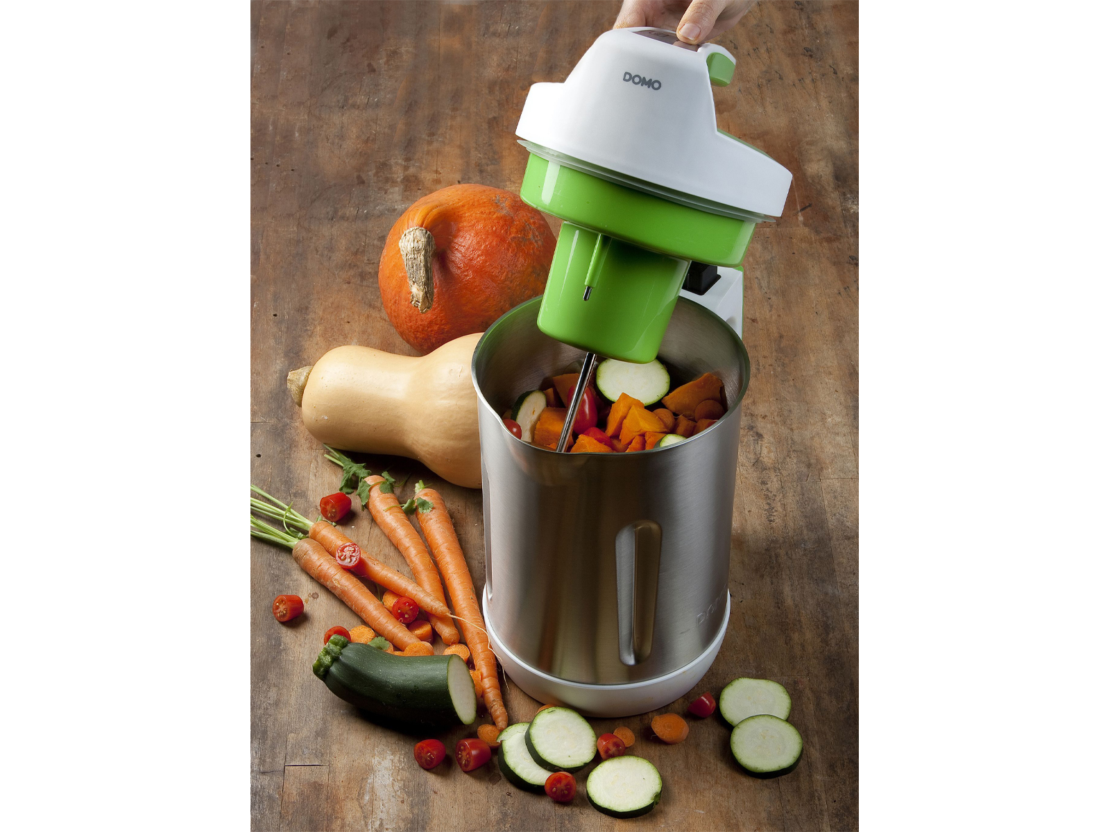 Verdure e un robot da cucina. Carote, zucchine, zucca e una macchina con un coperchio verde.