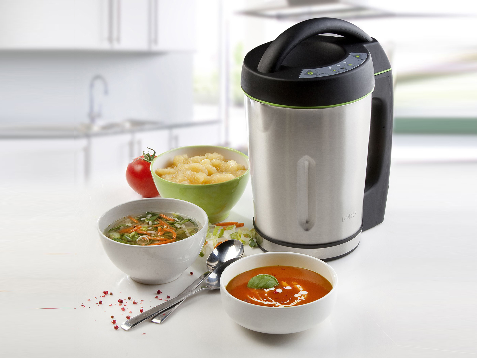 Un'apparecchiatura per la zuppa in acciaio inossidabile con manico nero e pannello di controllo, e ciotole di zuppa e ingredienti.